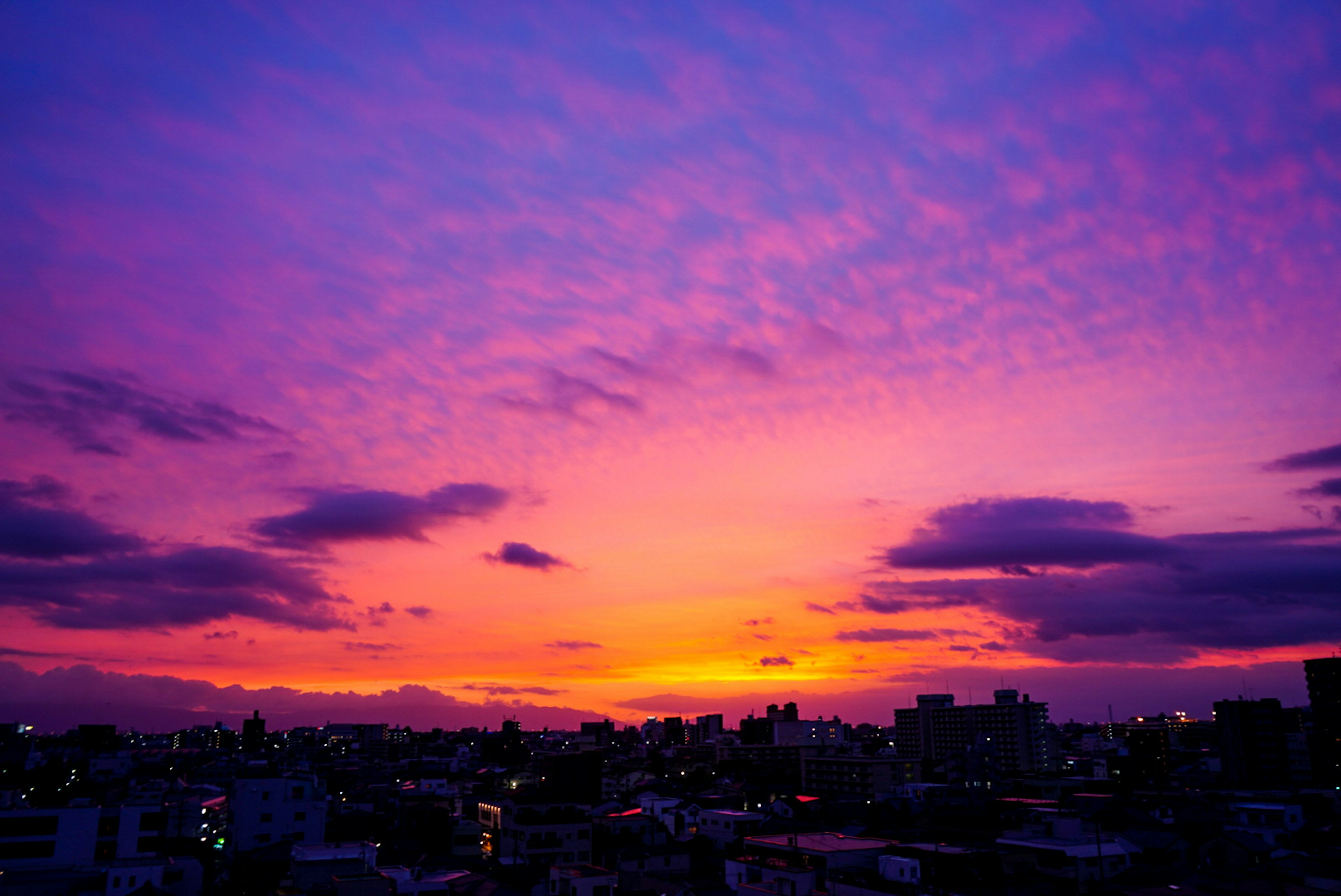 夕焼けの紫色の空と雲が広がる都市の風景