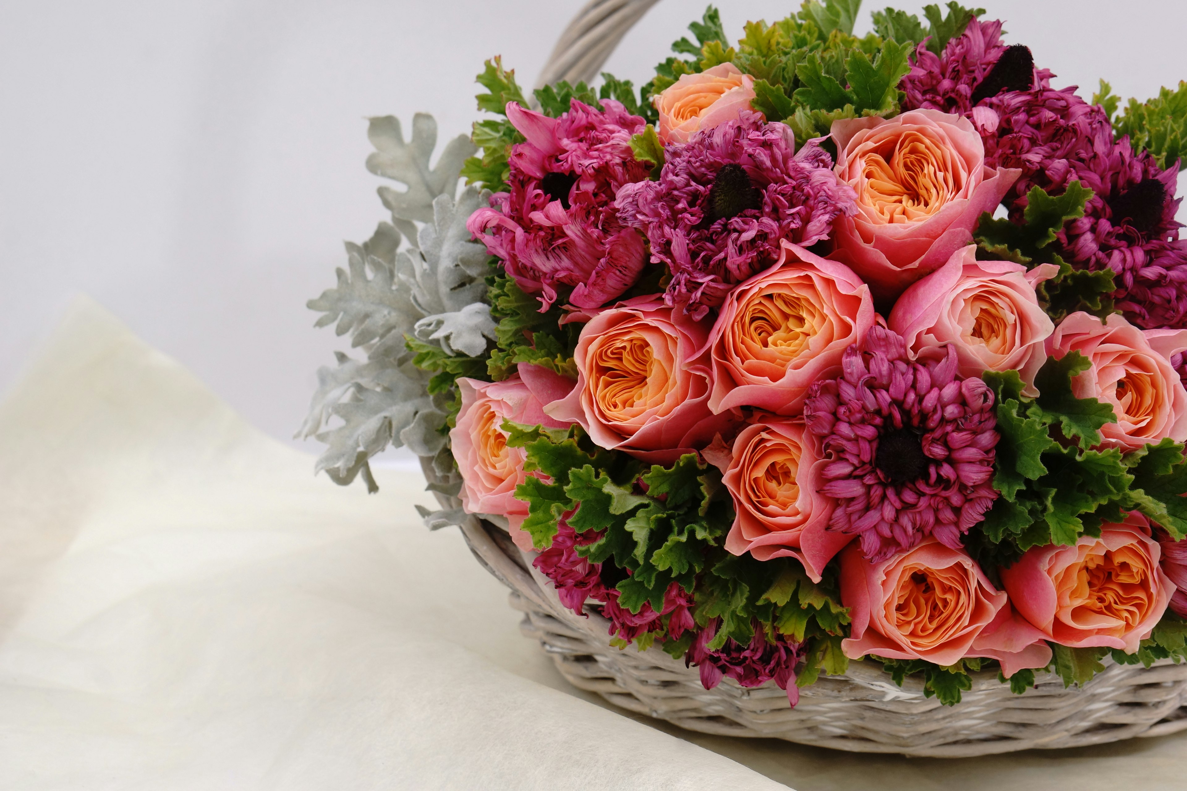 Basket filled with pink and orange roses and purple flowers