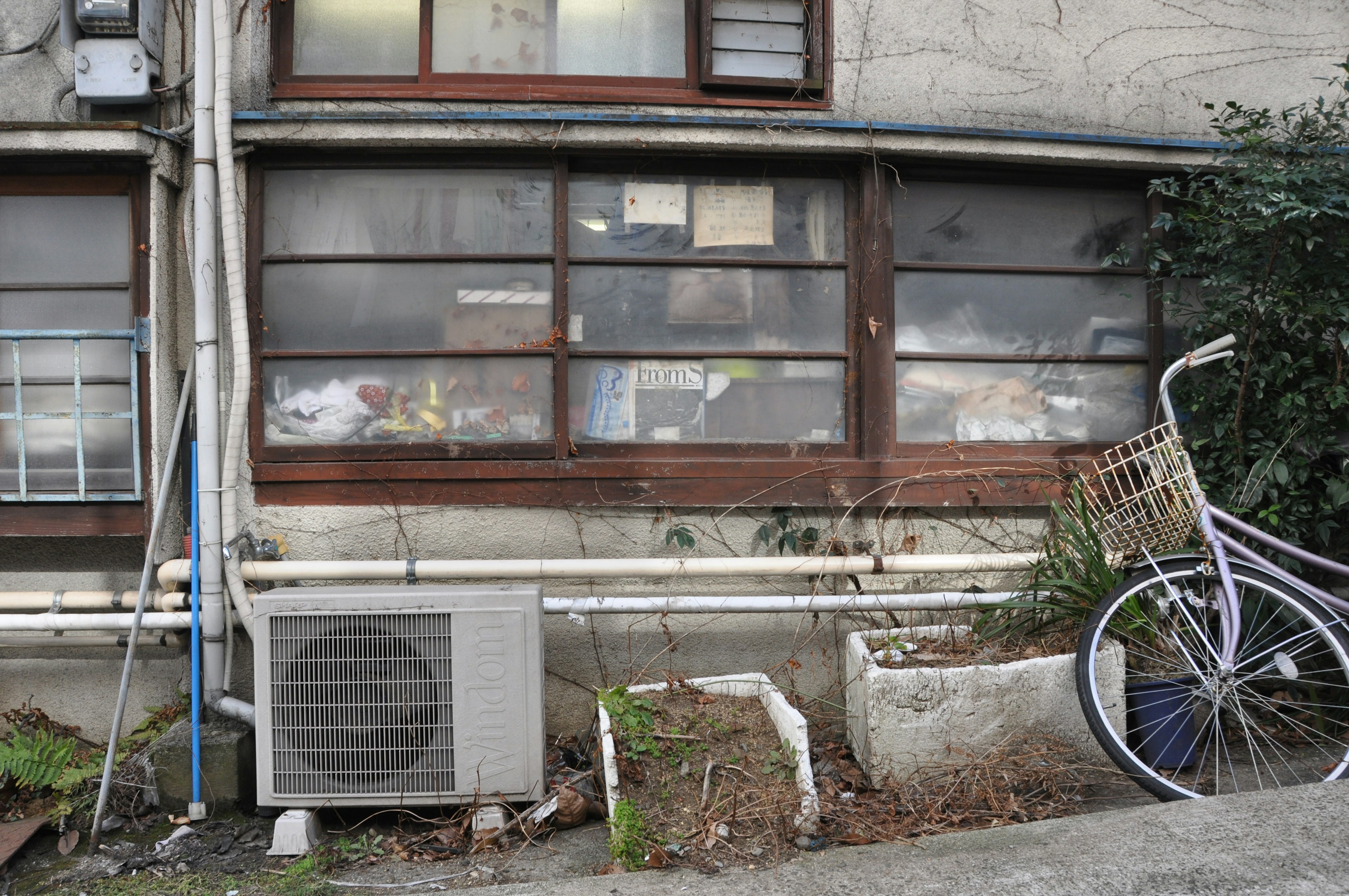 Außenansicht eines alten japanischen Gebäudefensters mit Fahrrad und Klimaanlage