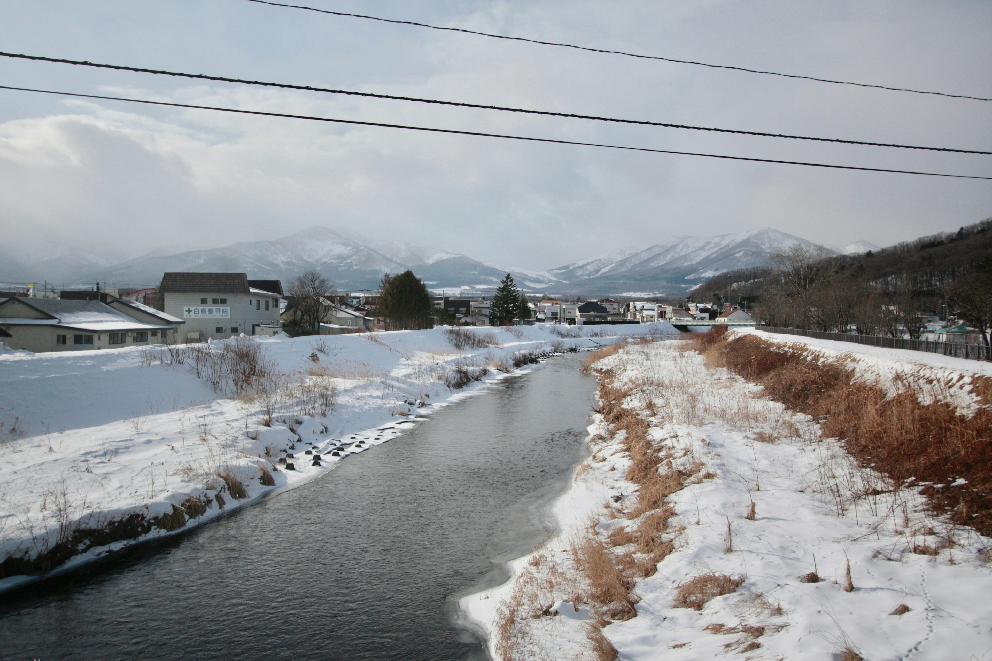 Schneebedeckte Flusslandschaft mit Bergen im Hintergrund