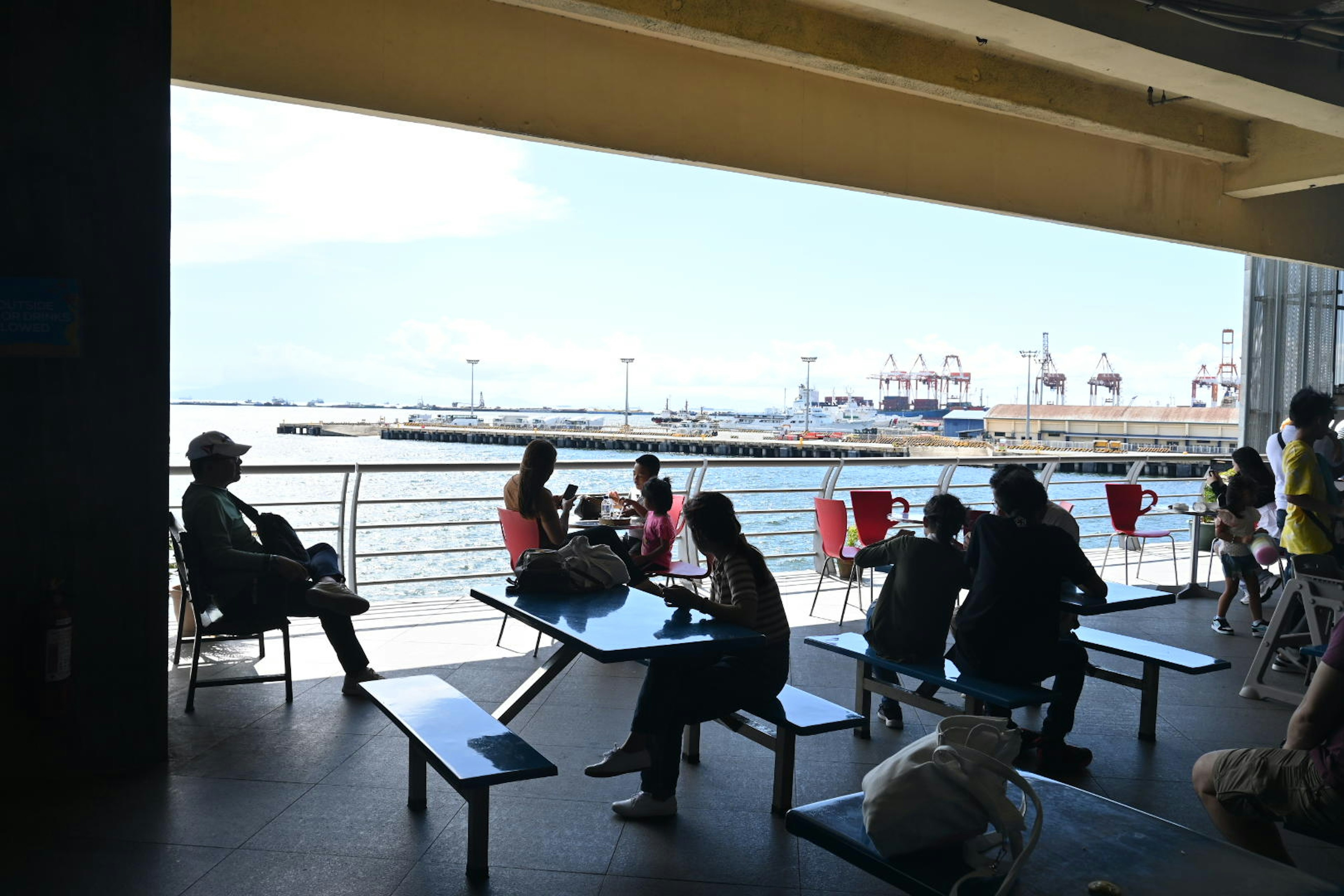 海を見渡すカフェのテラスで人々がくつろいでいる風景