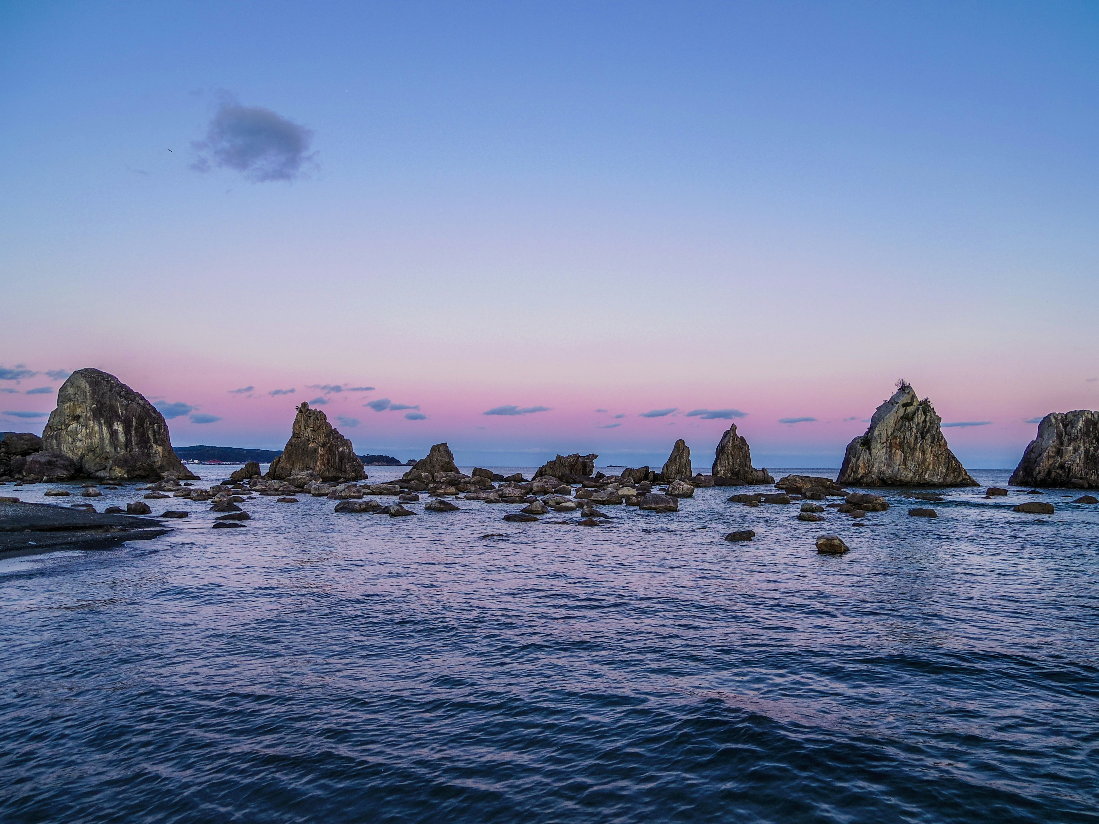 Felsenküste mit ruhigem Wasser und Sonnenuntergangstönen