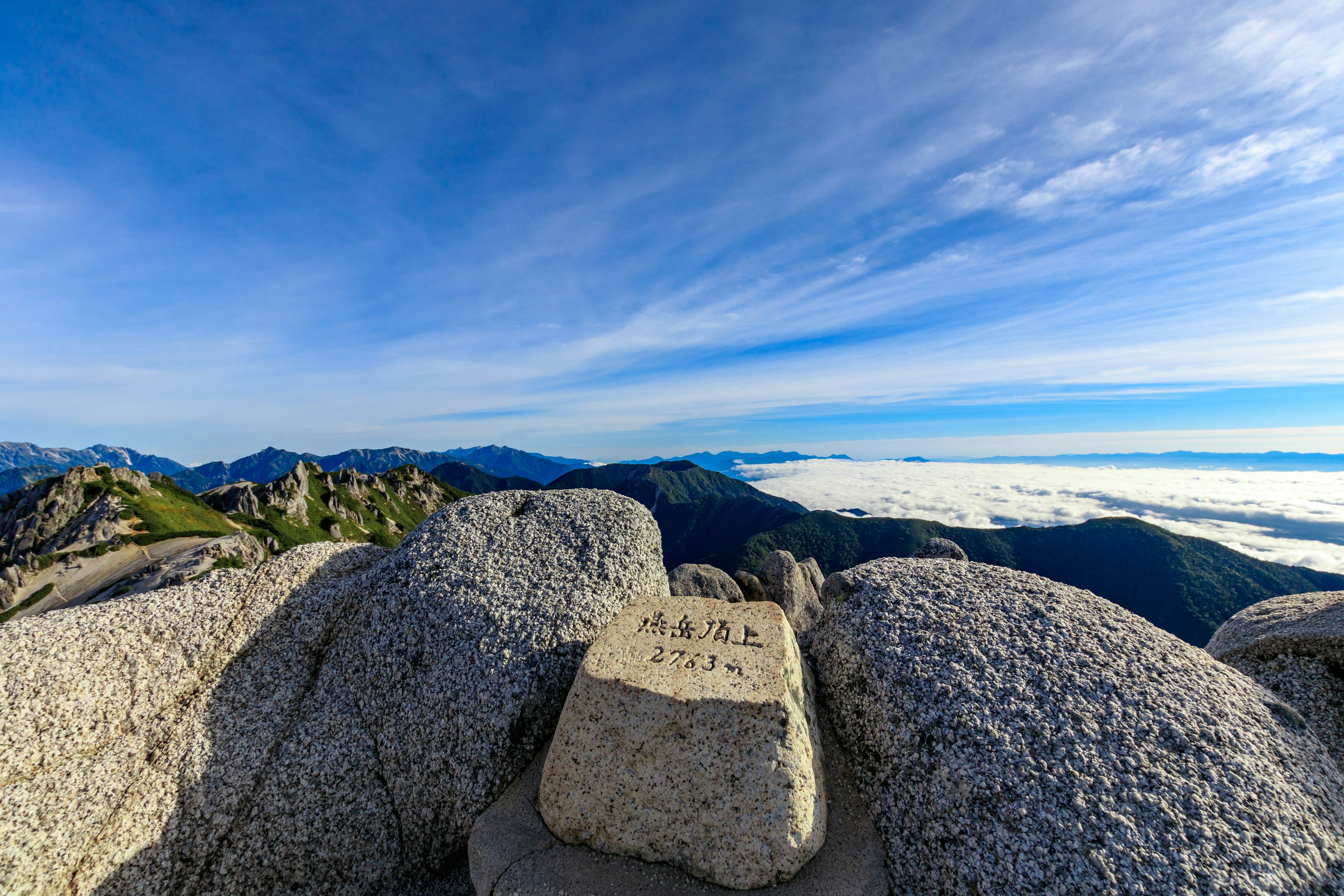 Panoramic view of mountains and sea of clouds under blue sky rock with a marker