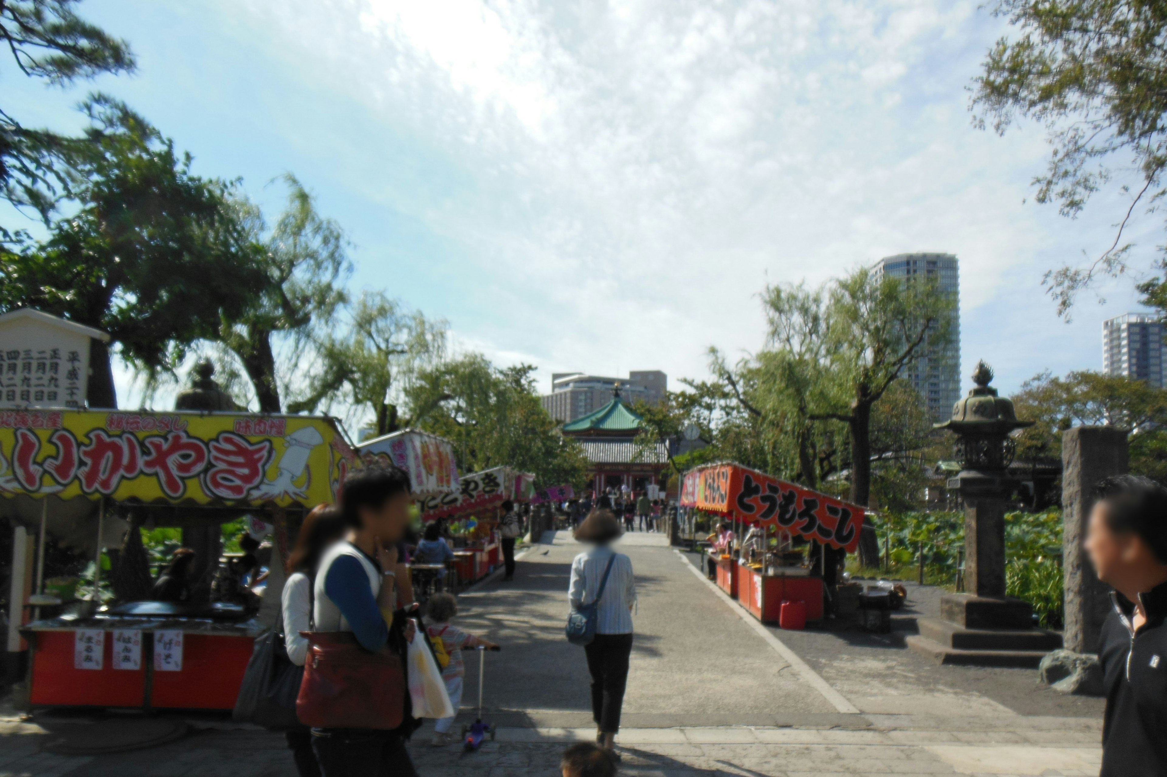 公园内热闹的街道，旁边是食品摊位和行走的人们