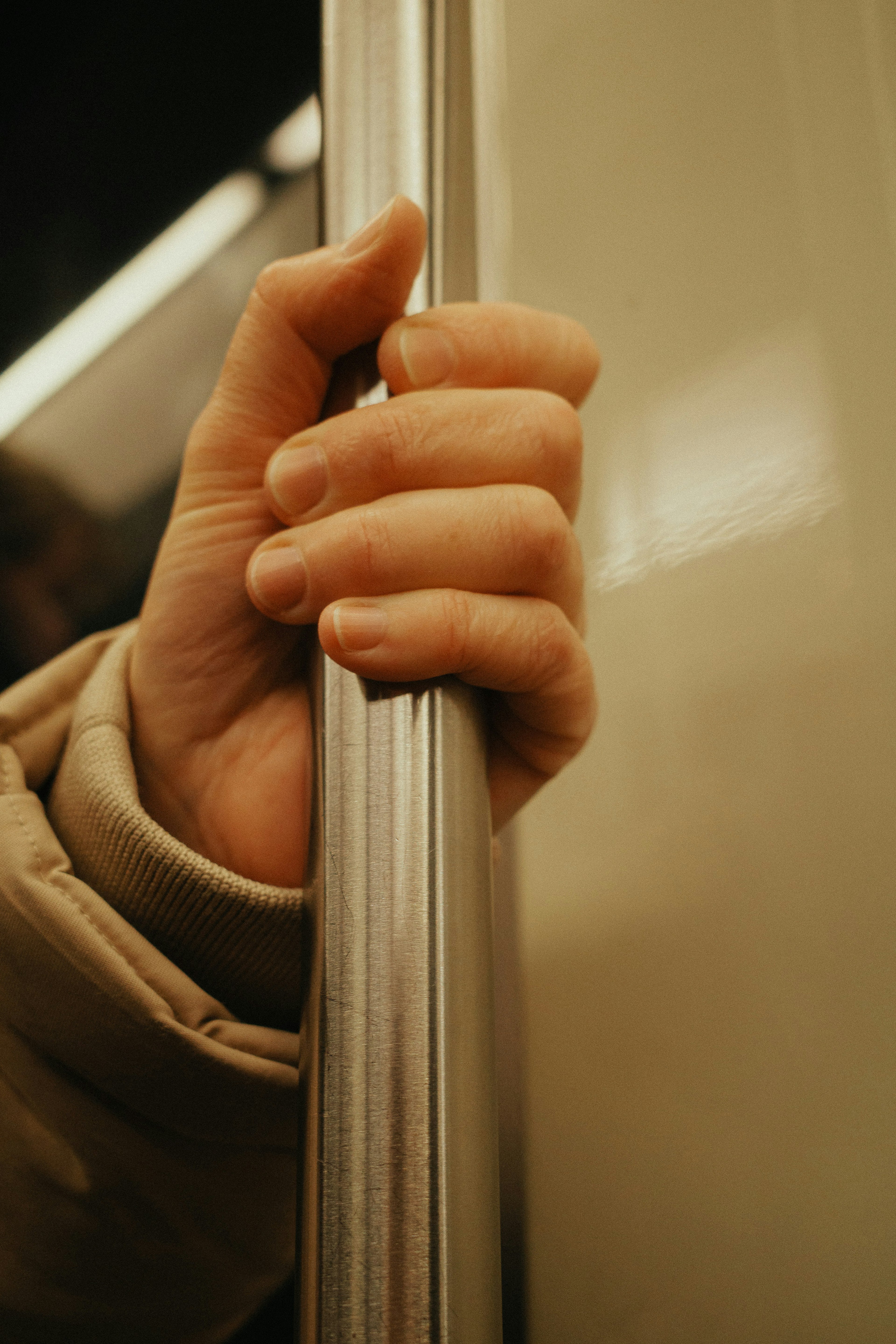 Una mano agarrando un pasamanos del metro