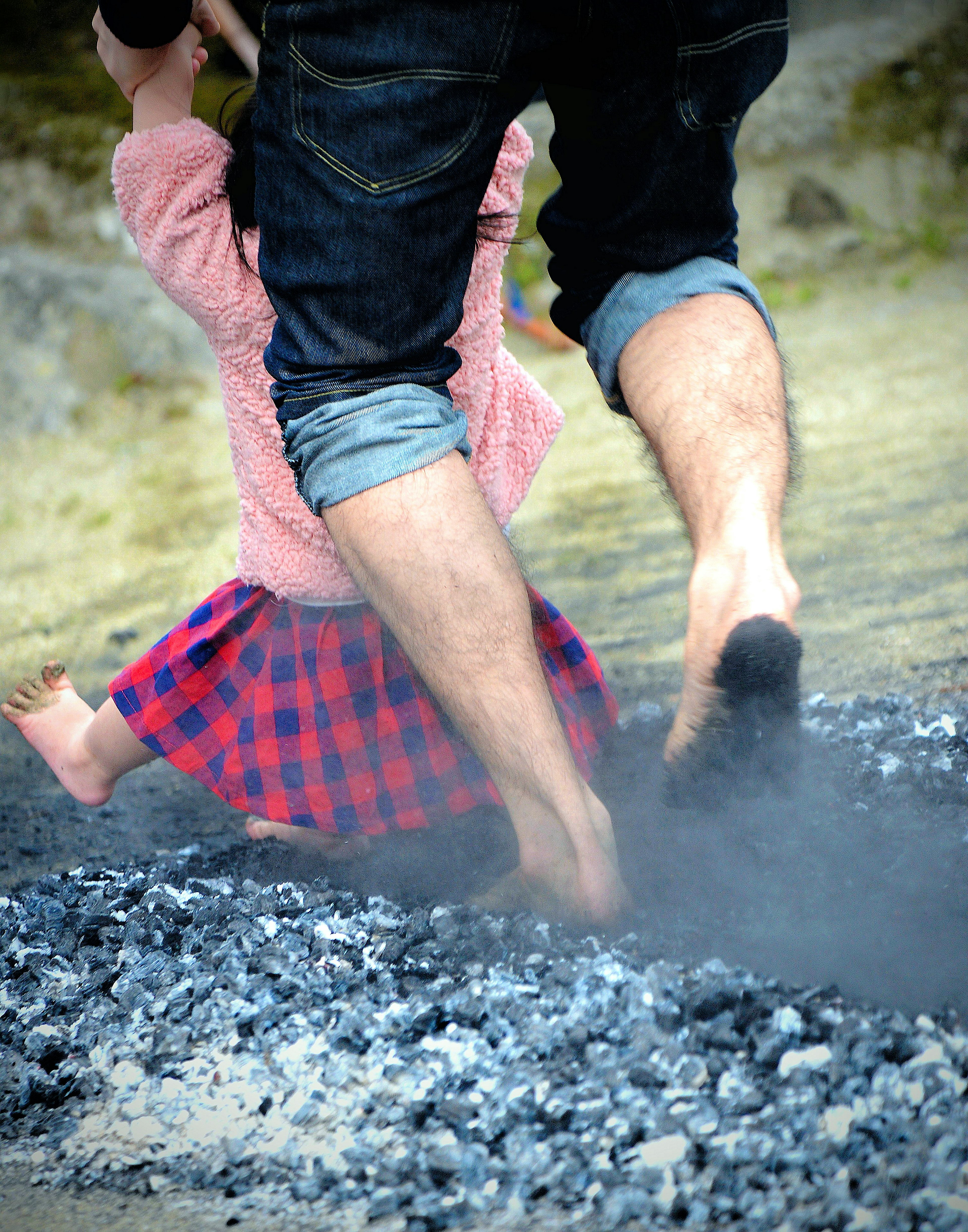 A father lifting a child wearing a pink sweater and a checkered skirt