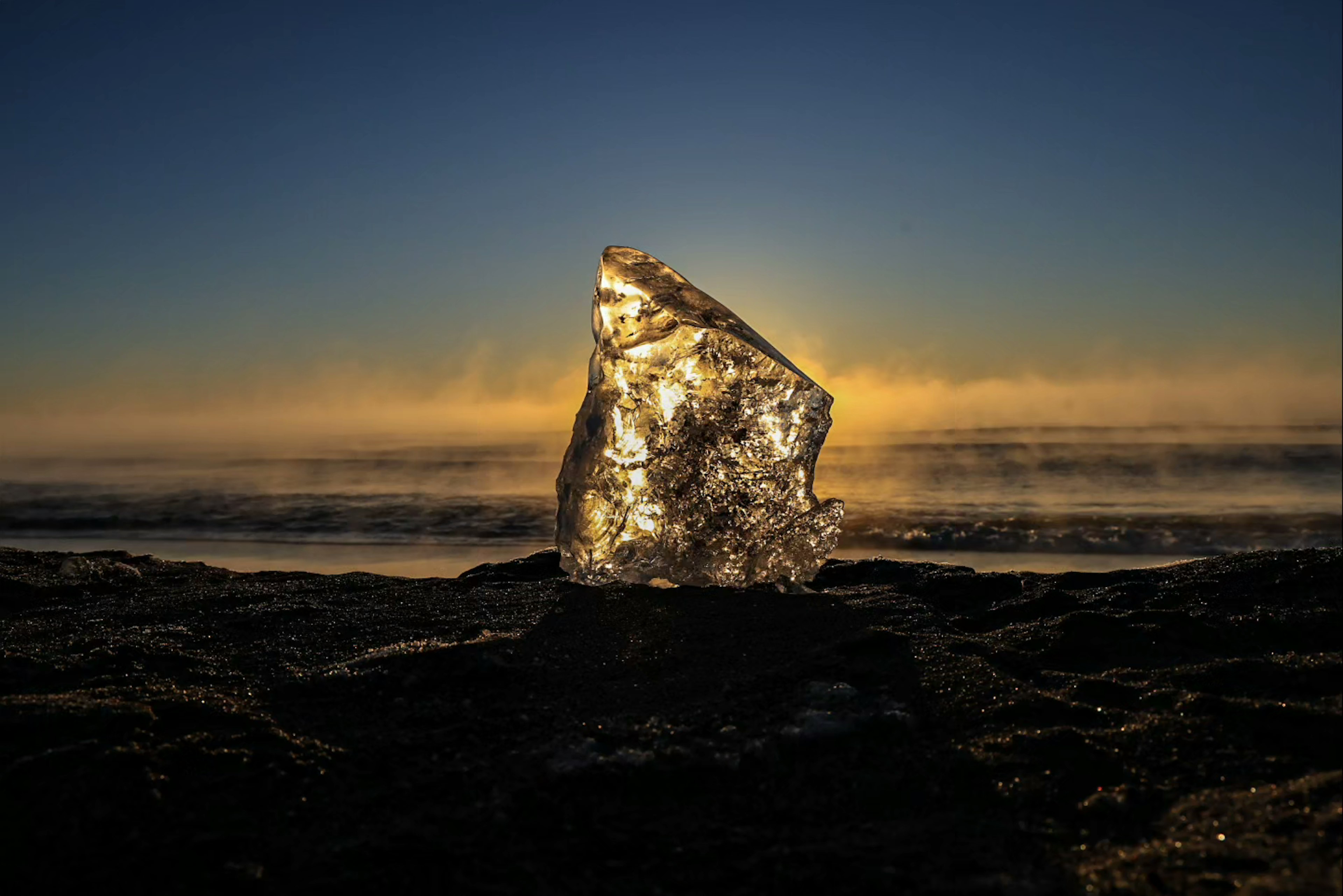 Rocher brillant sur le rivage avec un lever de soleil en arrière-plan