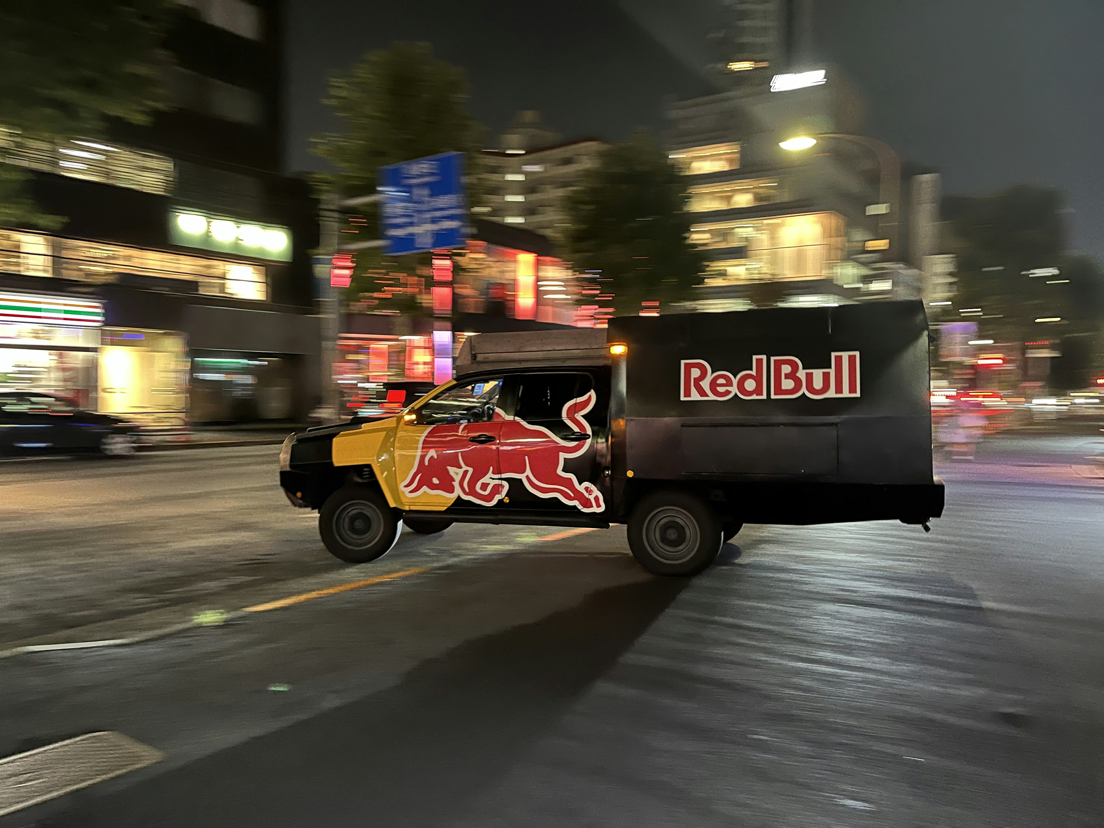 Camión con logo de Red Bull conduciendo por la ciudad de noche