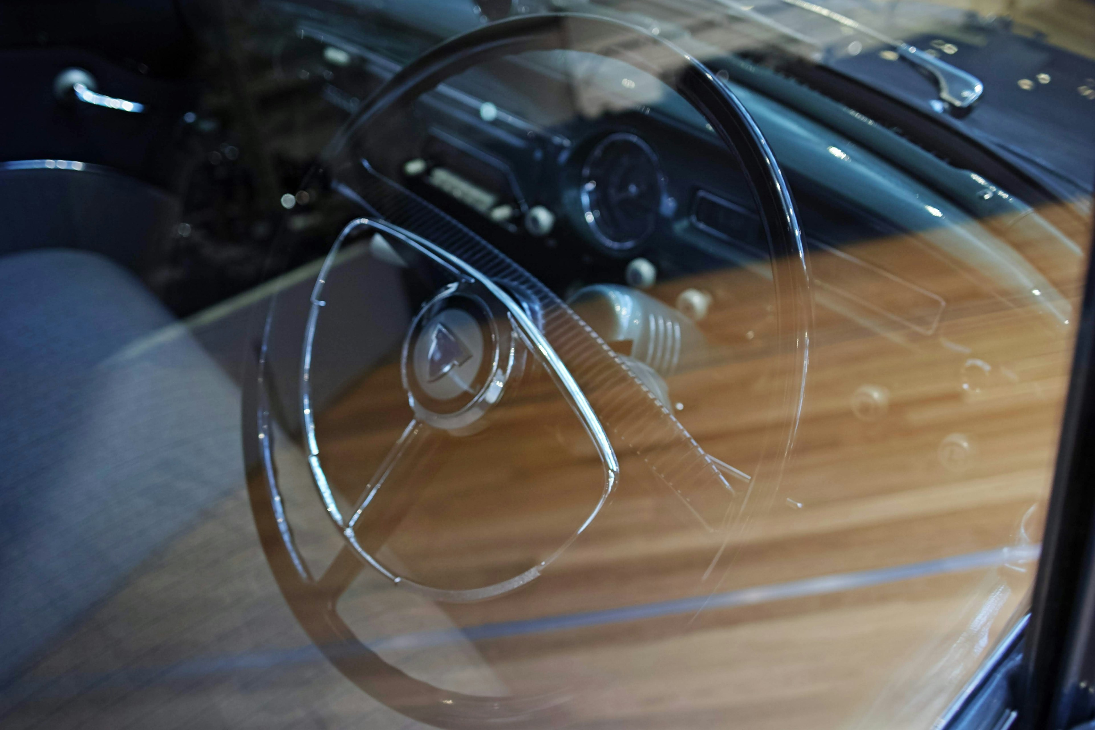 Close-up of a vintage car steering wheel and wooden dashboard