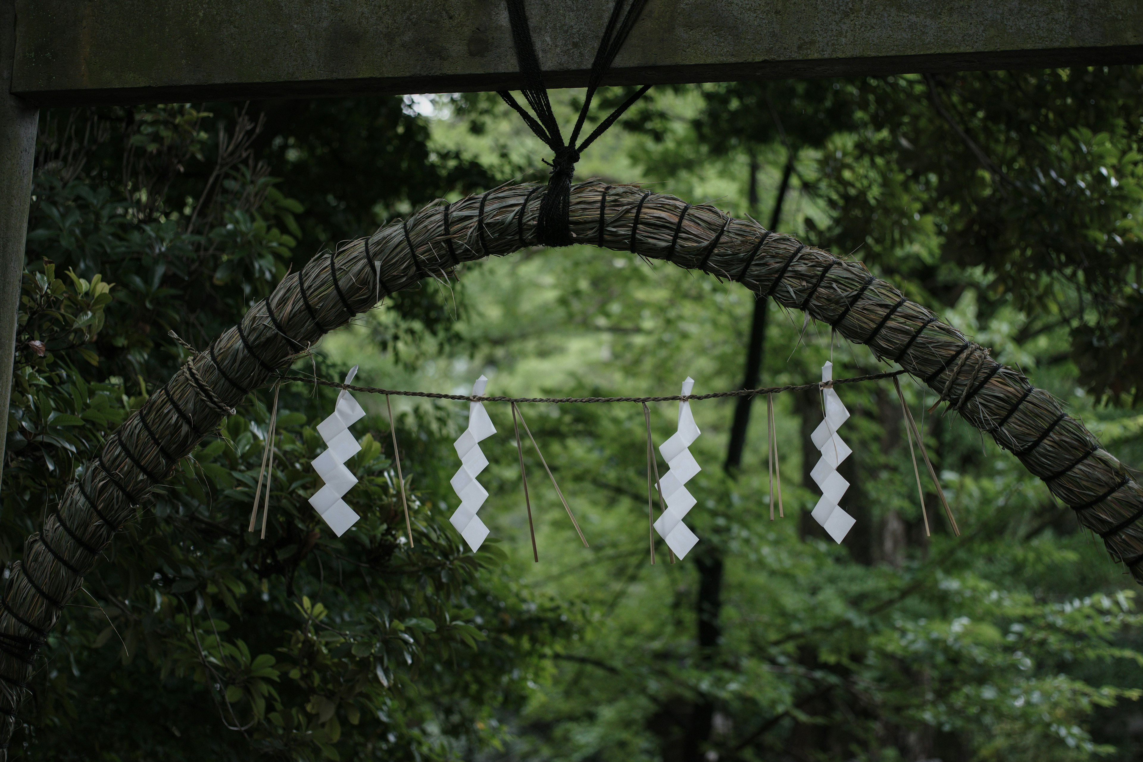 A natural arch made of rope with white decorations hanging