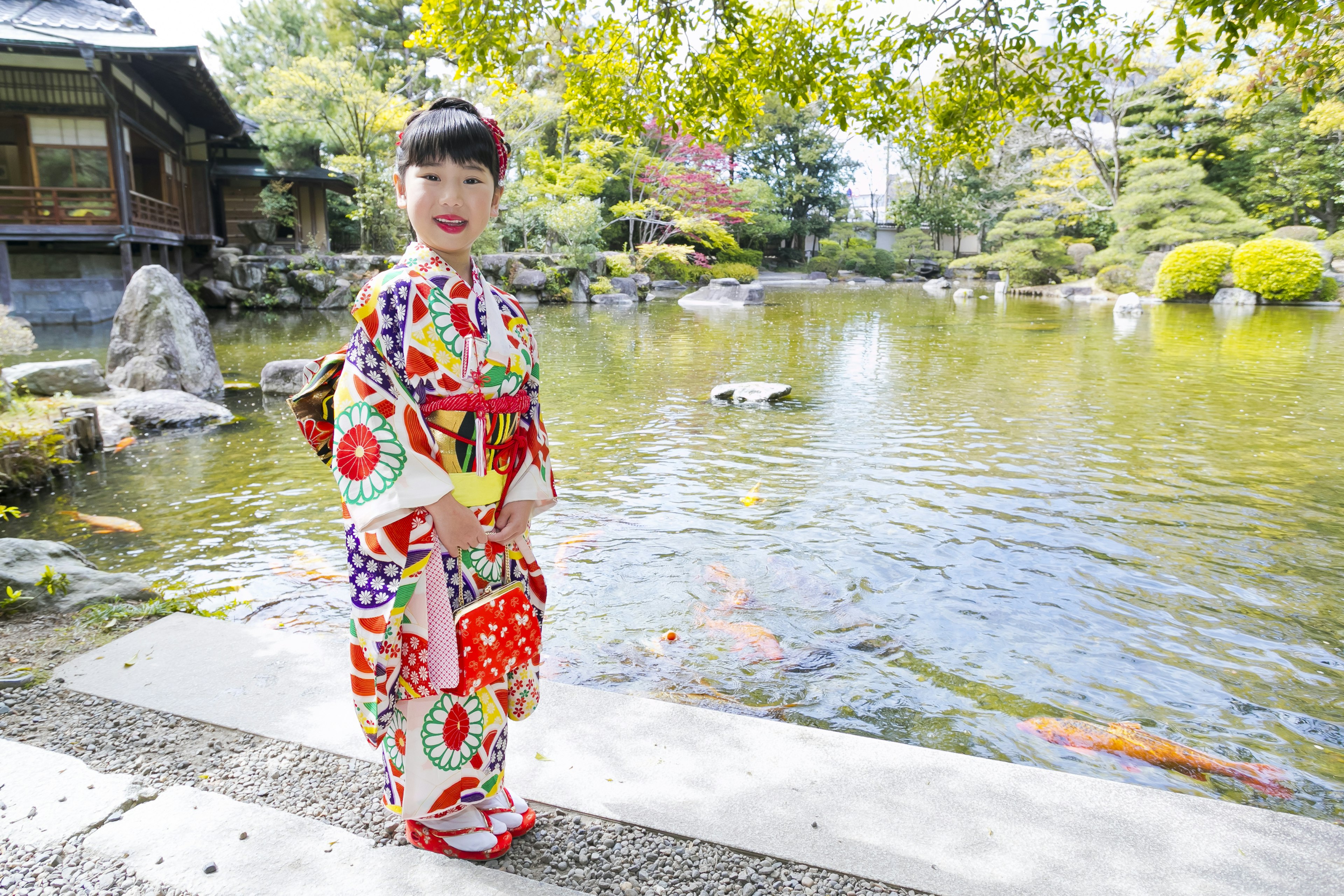 Một cô gái trong trang phục kimono truyền thống của Nhật Bản đứng bên ao