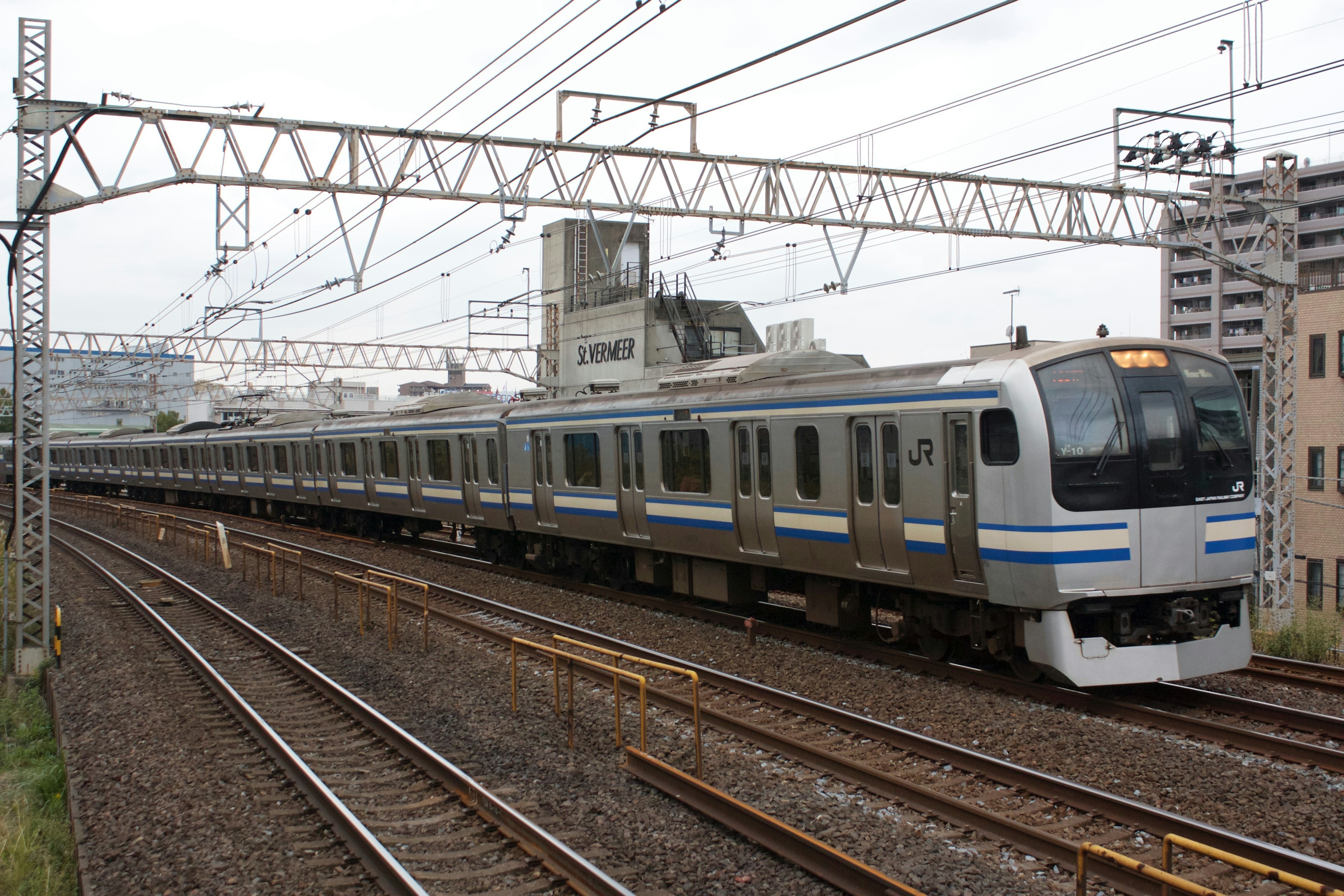 รถไฟที่มีลายสีน้ำเงินวิ่งผ่านภูมิทัศน์ในเมือง