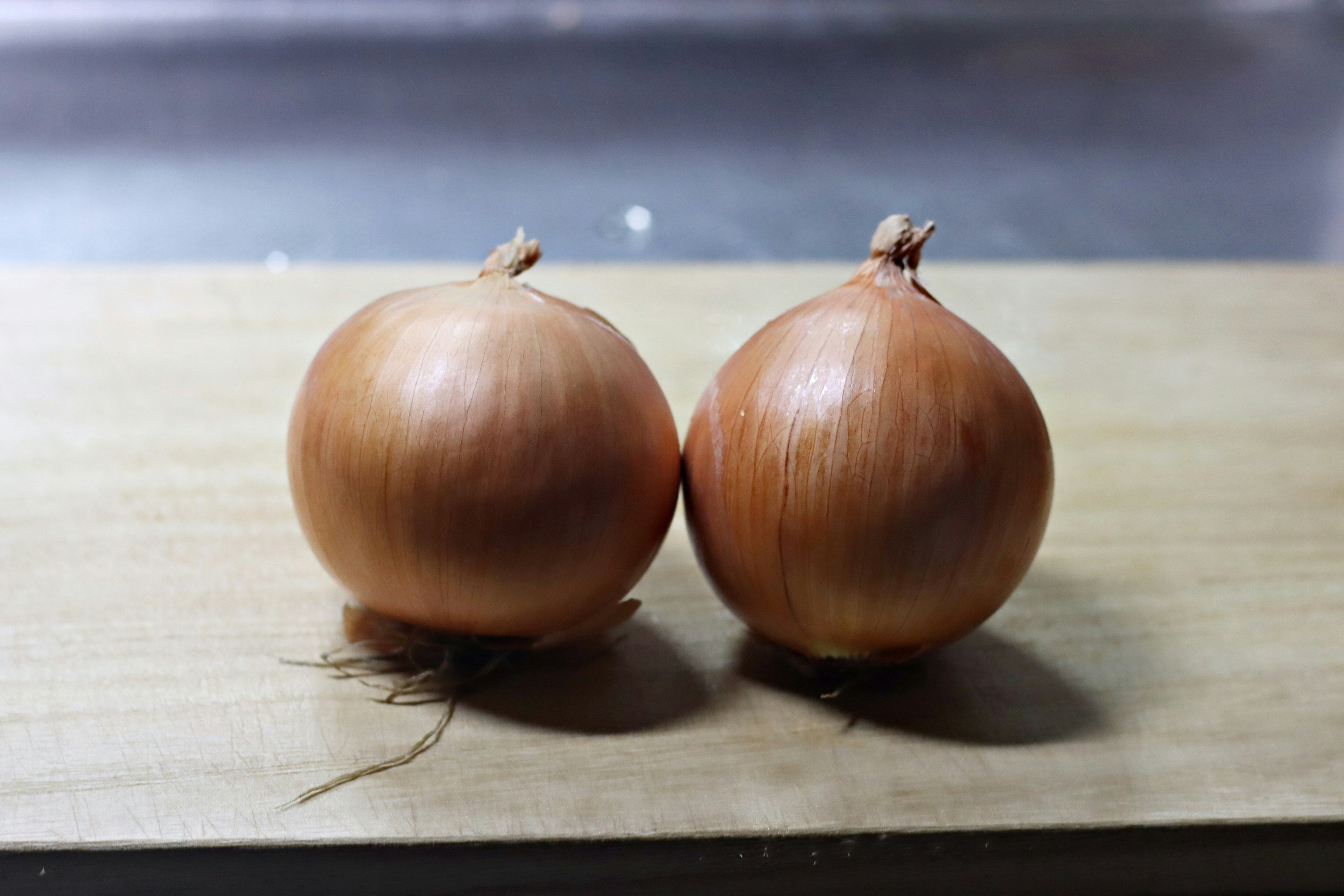 Two onions placed on a wooden board