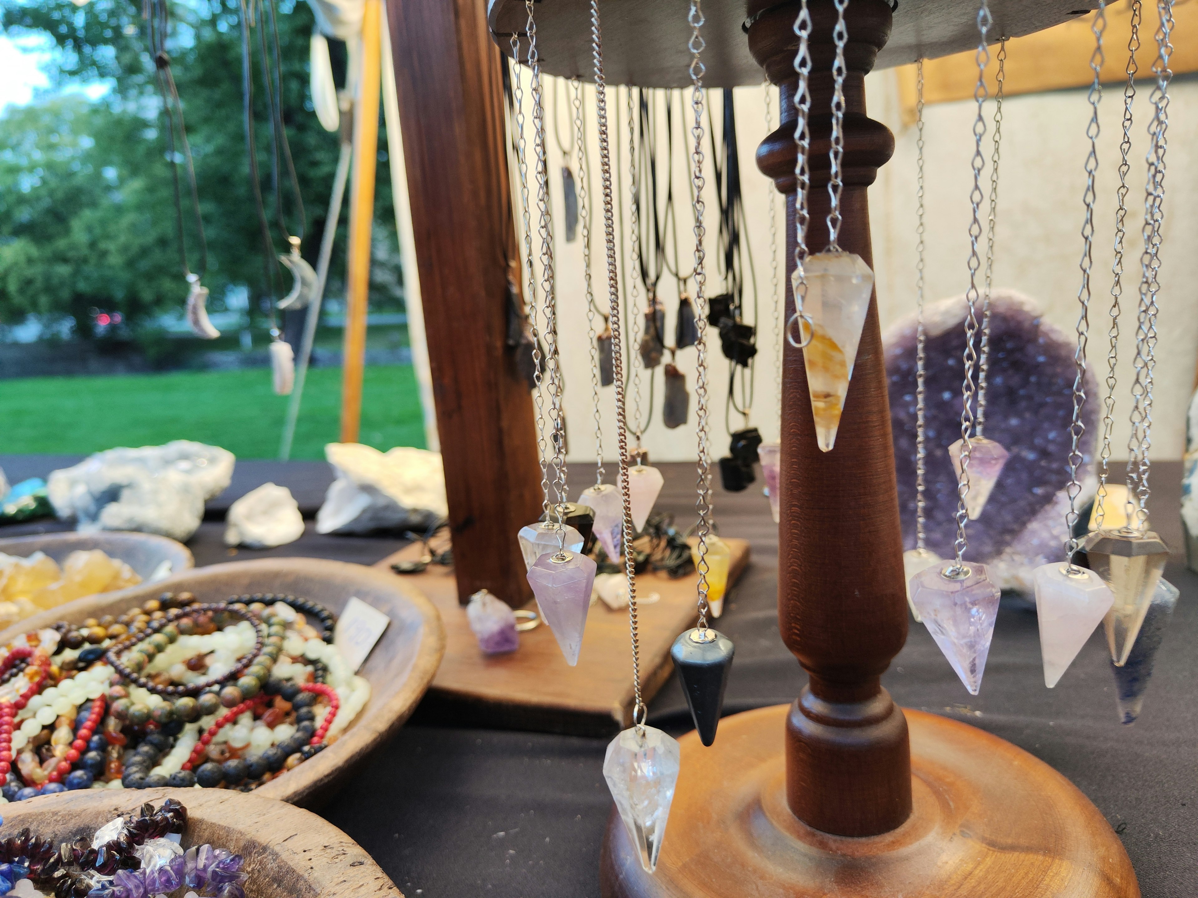 Exhibición de hermosos collares de cristal colgados de un soporte de madera con varias piedras preciosas