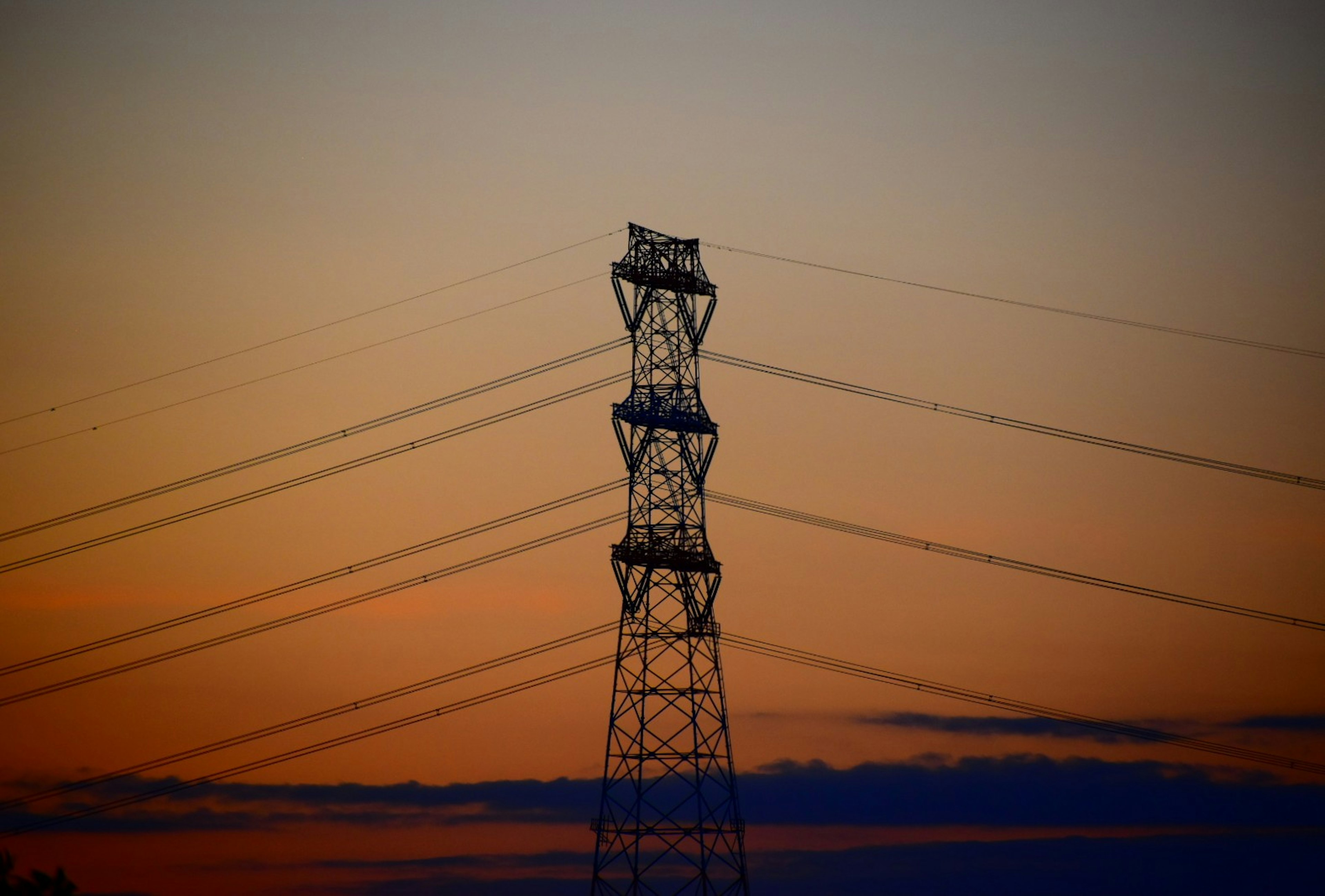 High voltage power tower against a sunset sky