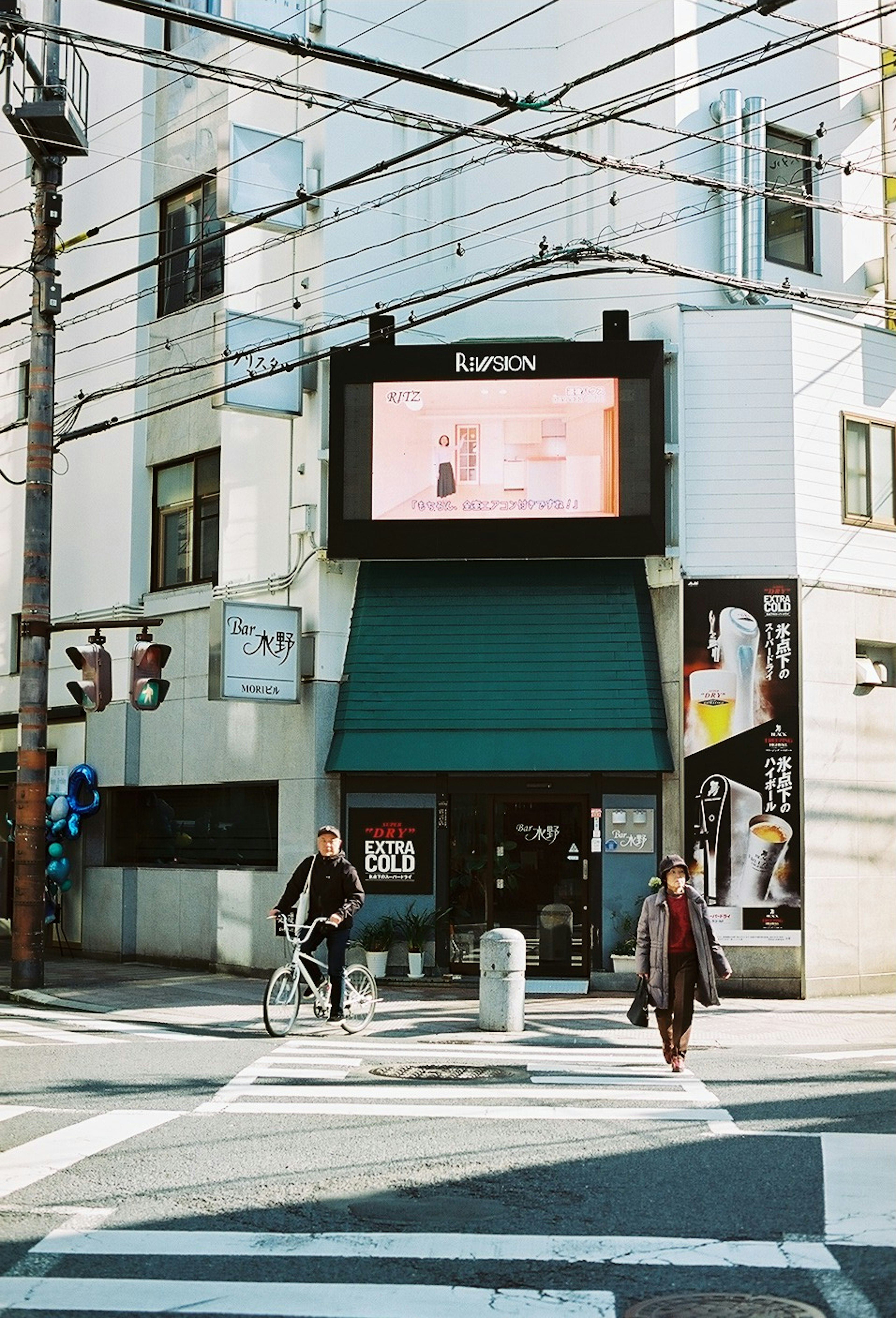 交差点にあるビルと緑の屋根の店舗を背景にした街の風景