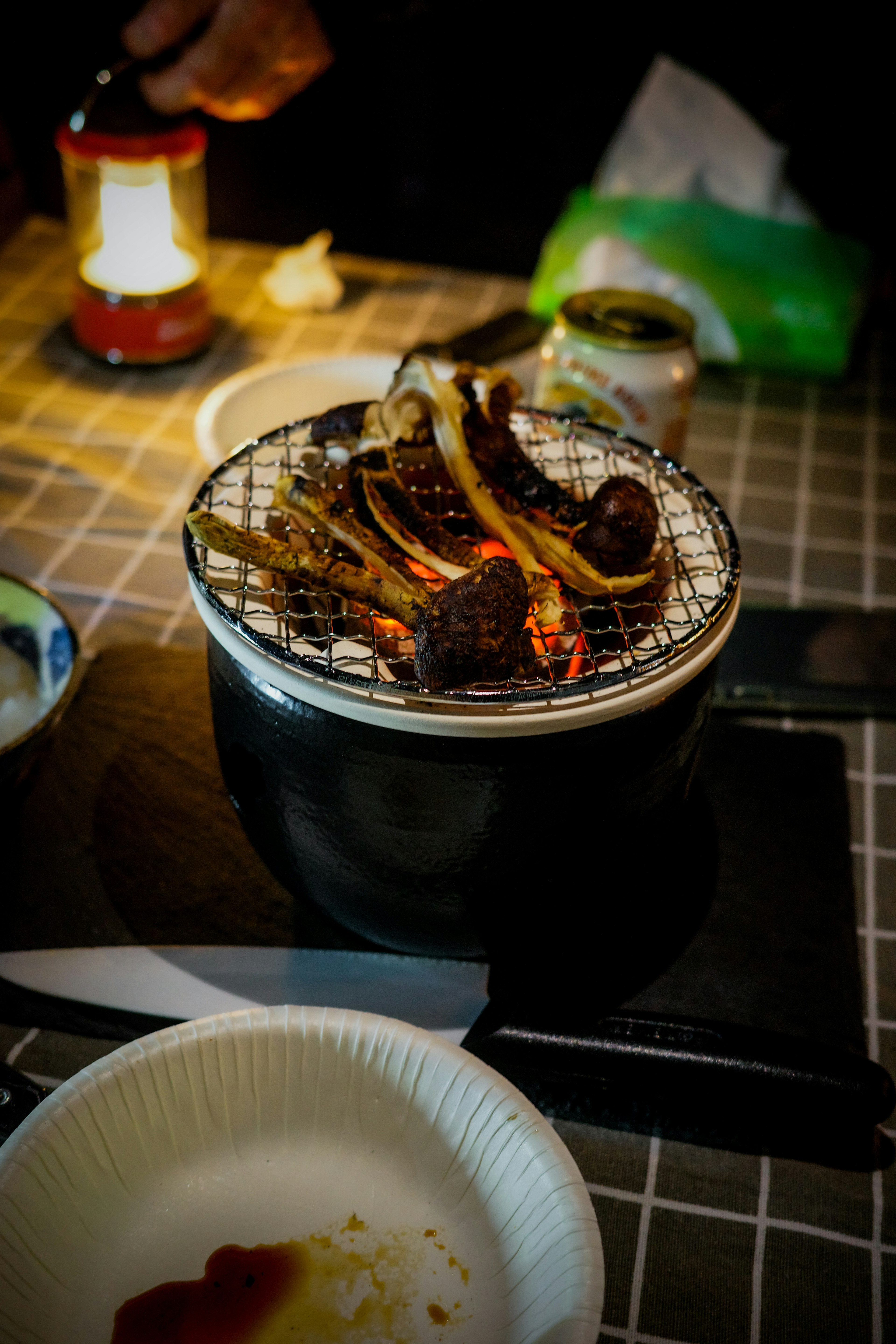 テーブルの上で焼かれている肉の串焼きとランプの光