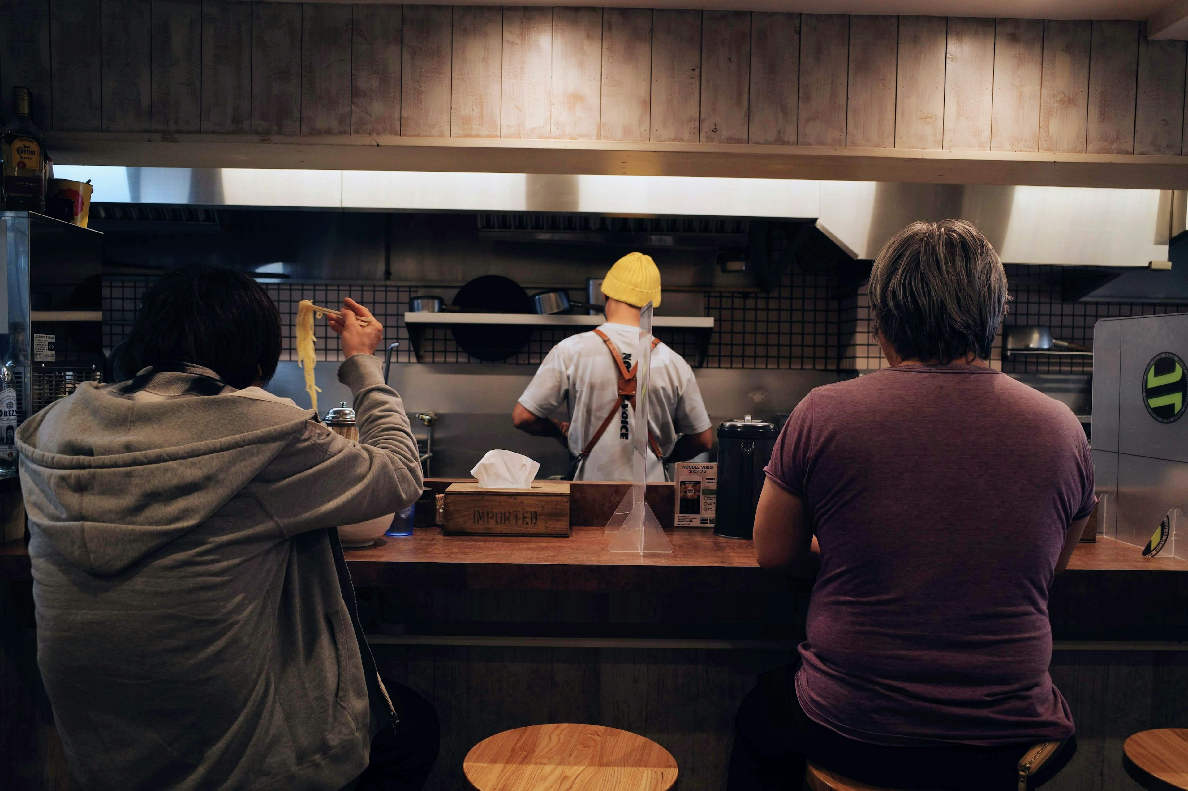 Scene of a chef cooking at the counter with two customers seated