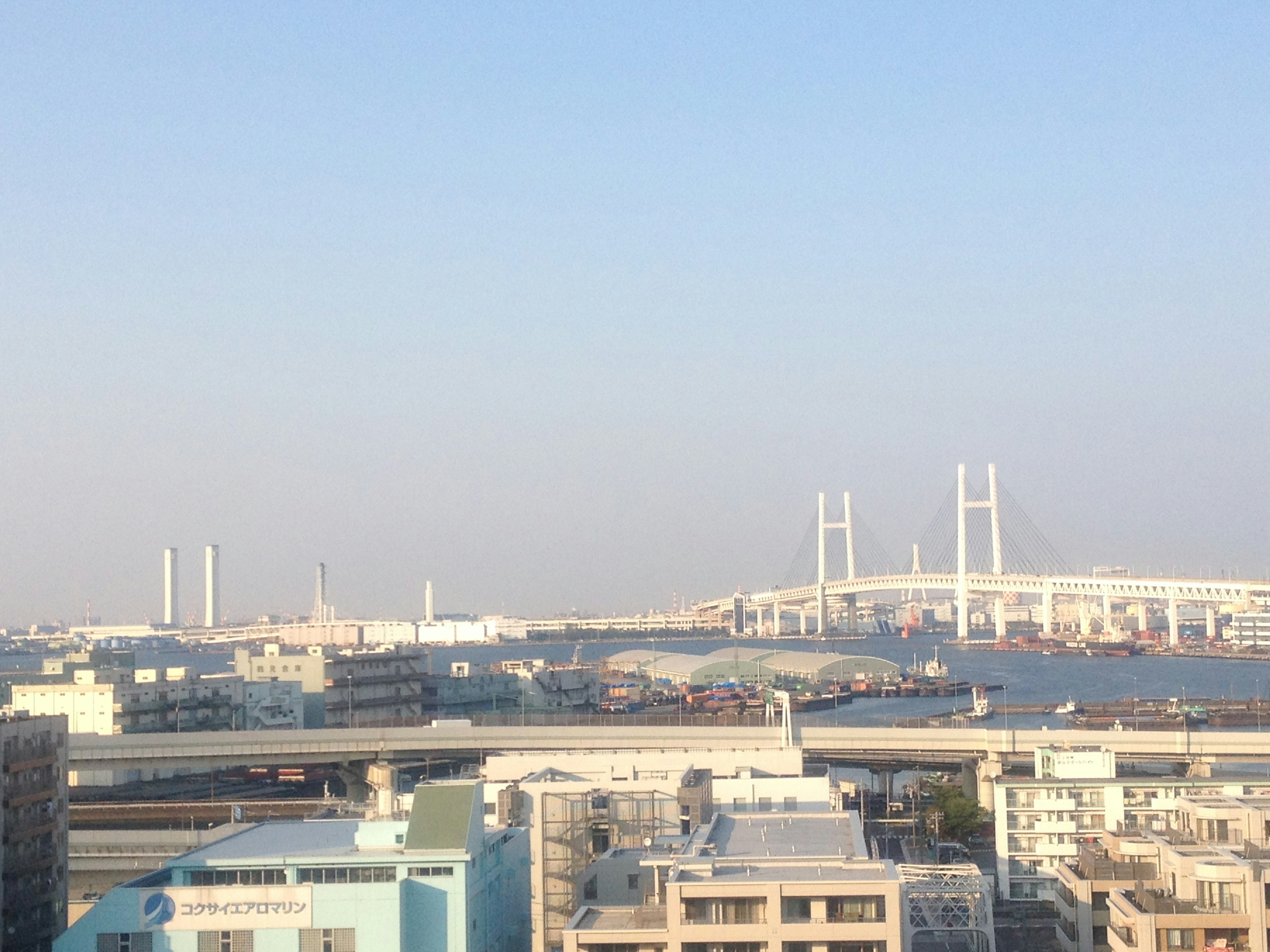 Vista del porto e dello skyline di Yokohama sotto un cielo azzurro chiaro con un ponte