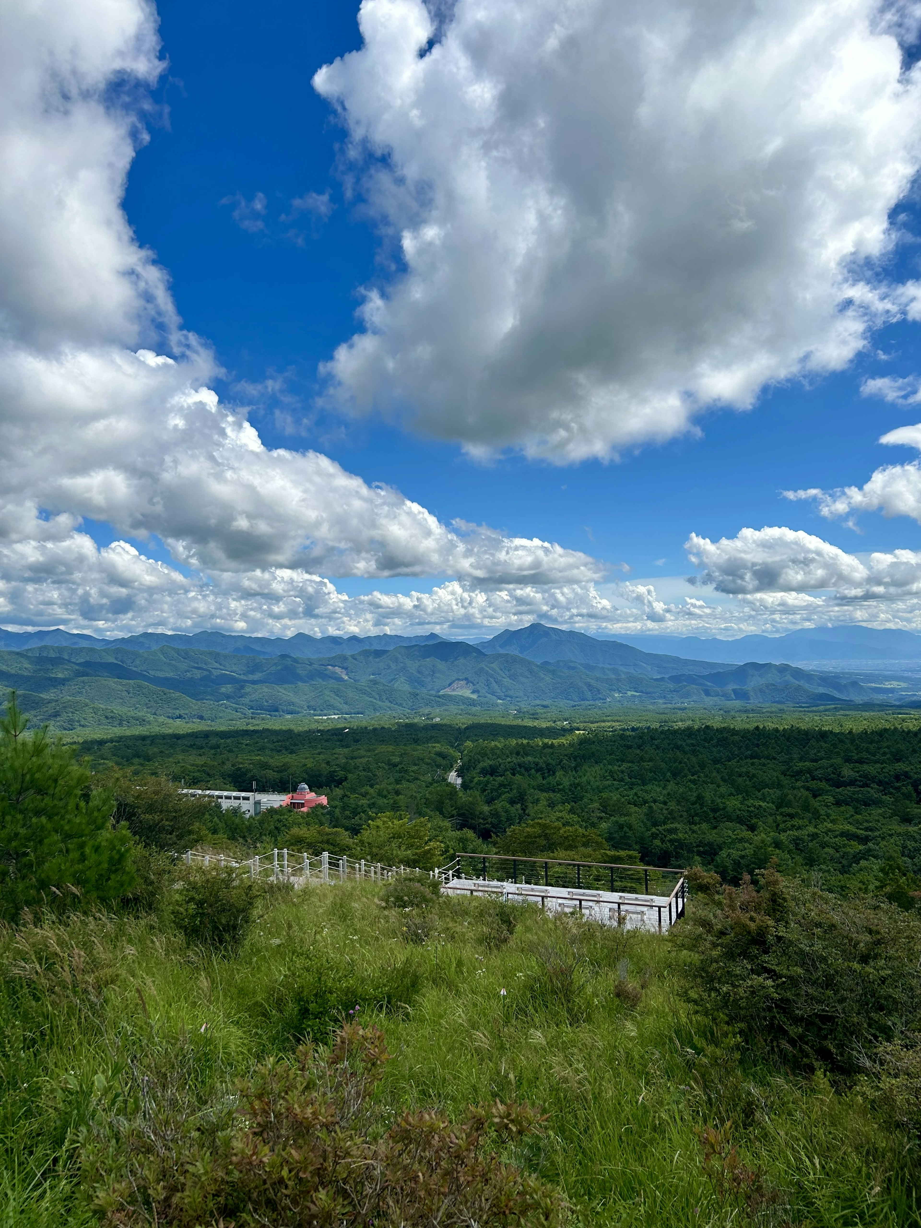 Scenic view of mountains under blue sky with clouds lush green hills and houses visible