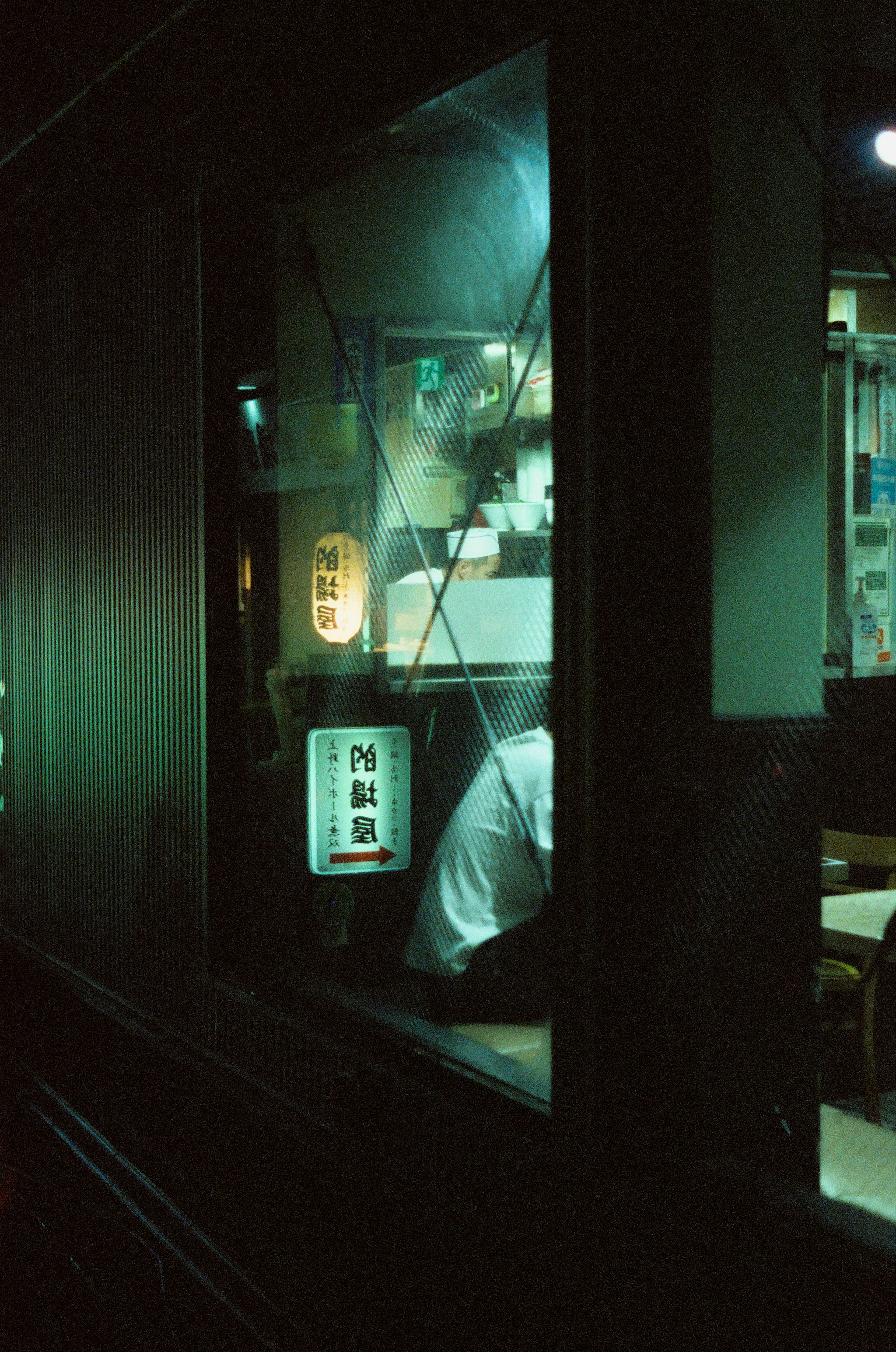 Interior débilmente iluminado de un restaurante con un chef preparando comida