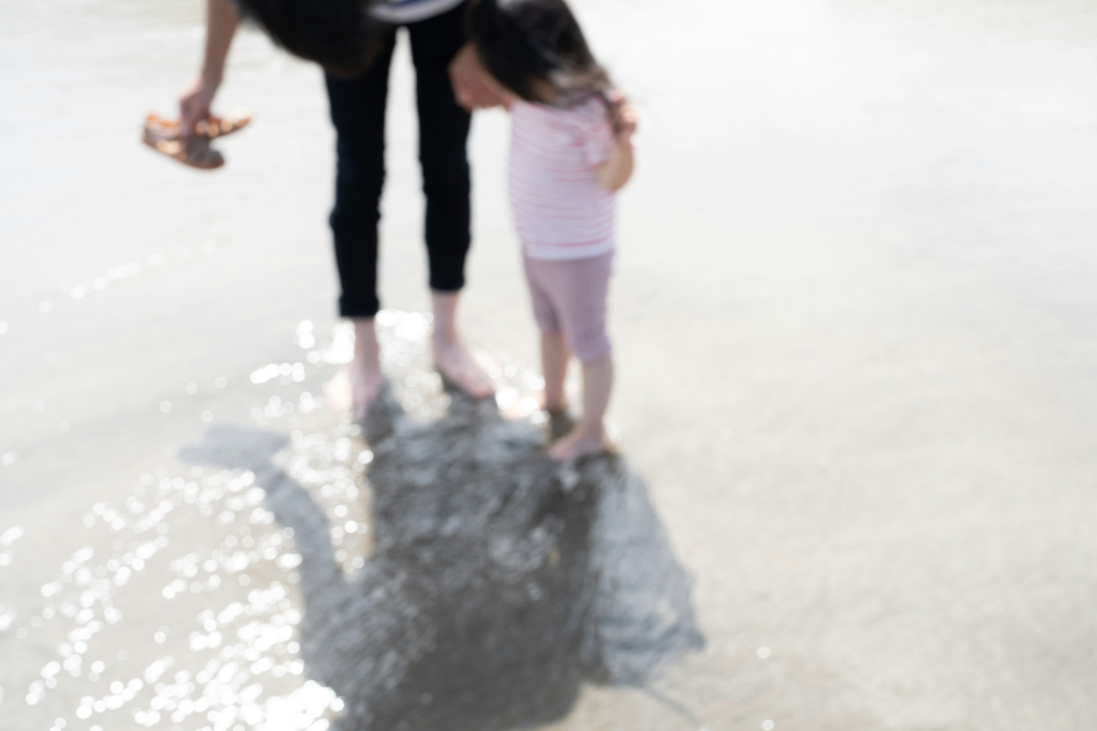 Silhouette of a parent and child standing in shallow water at the beach