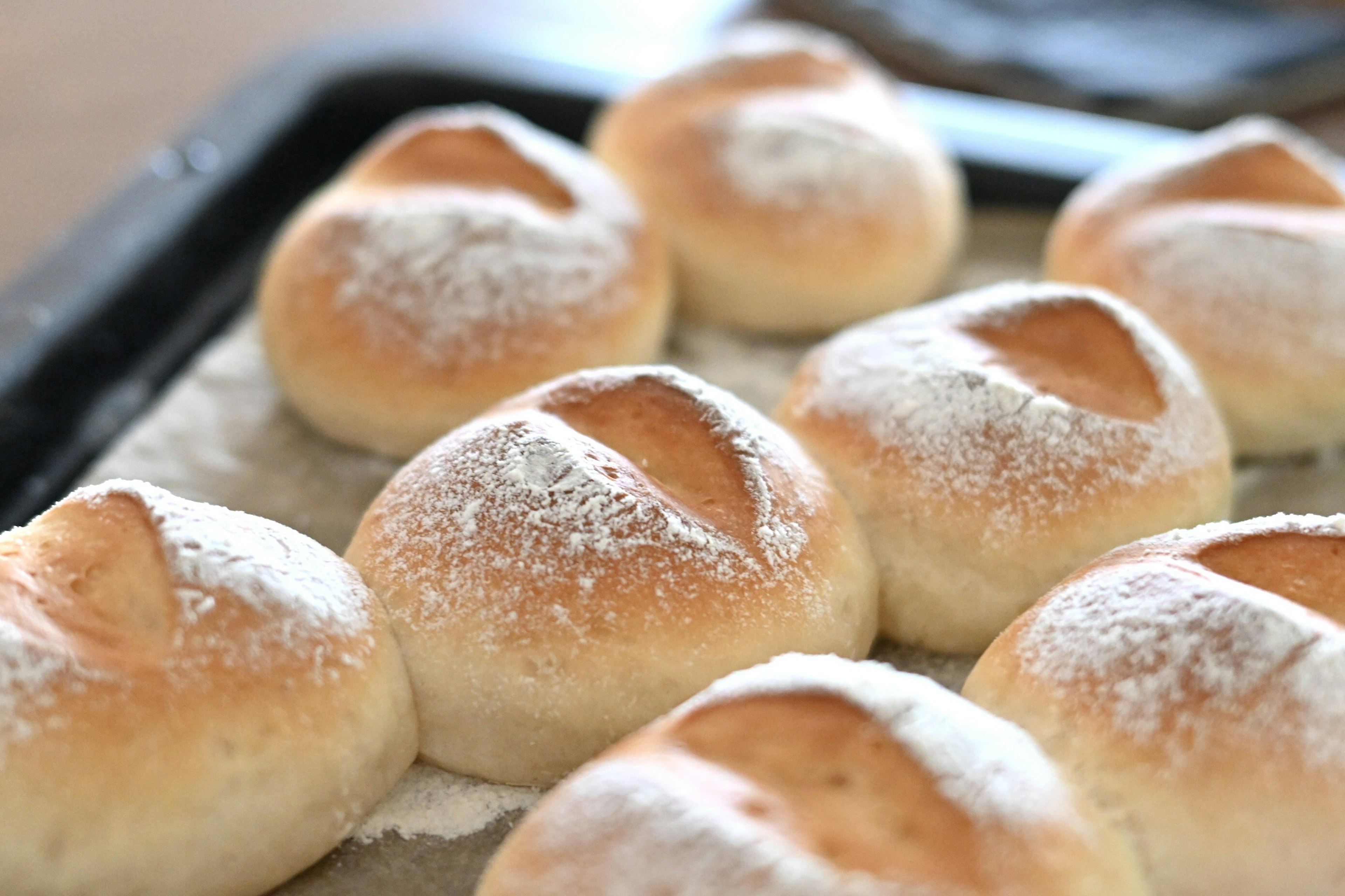 Frisch gebackene Brötchen auf einem Blech mit einem leichten Staub aus Mehl oben