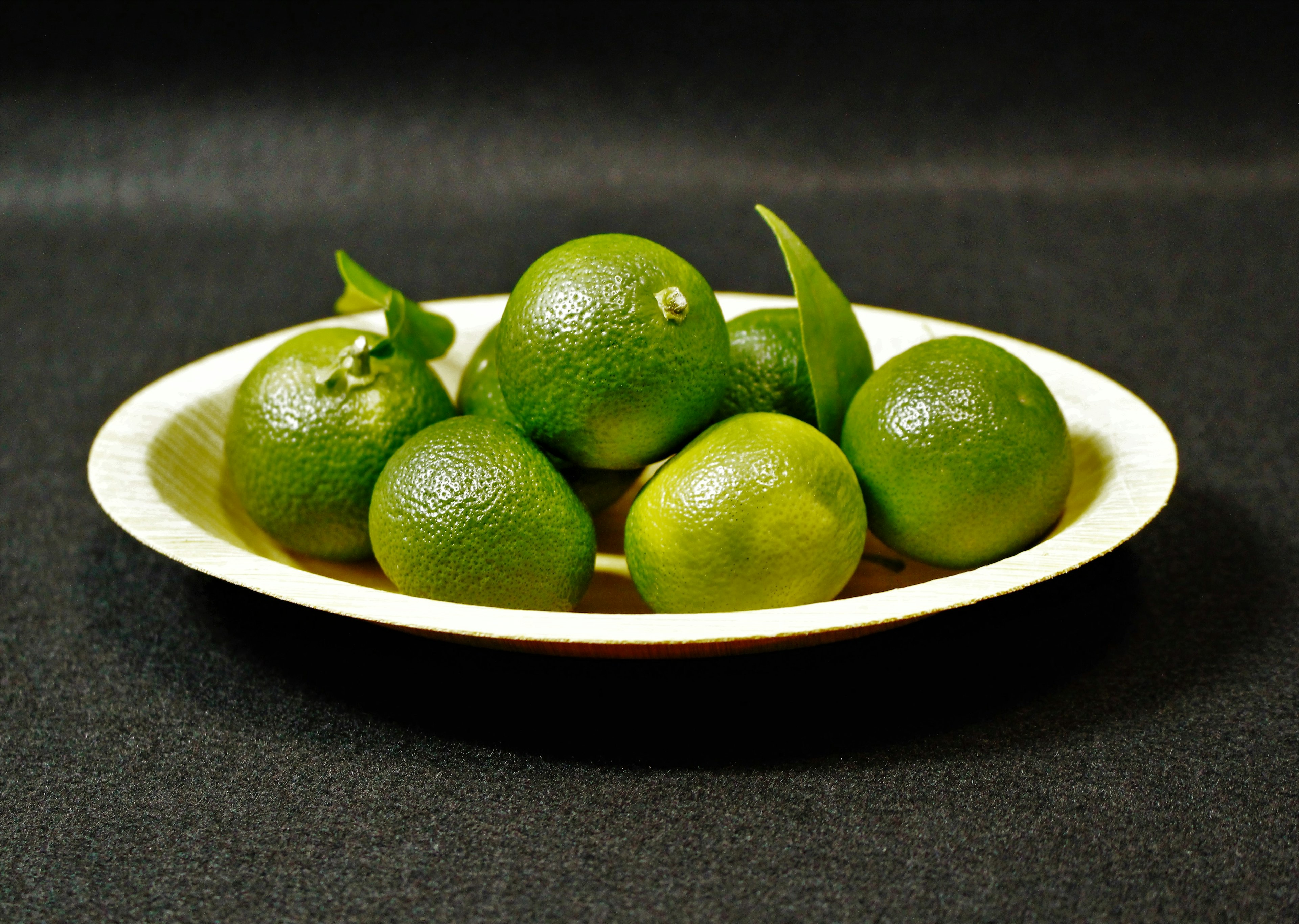 Pequeñas frutas cítricas verdes dispuestas en un plato blanco