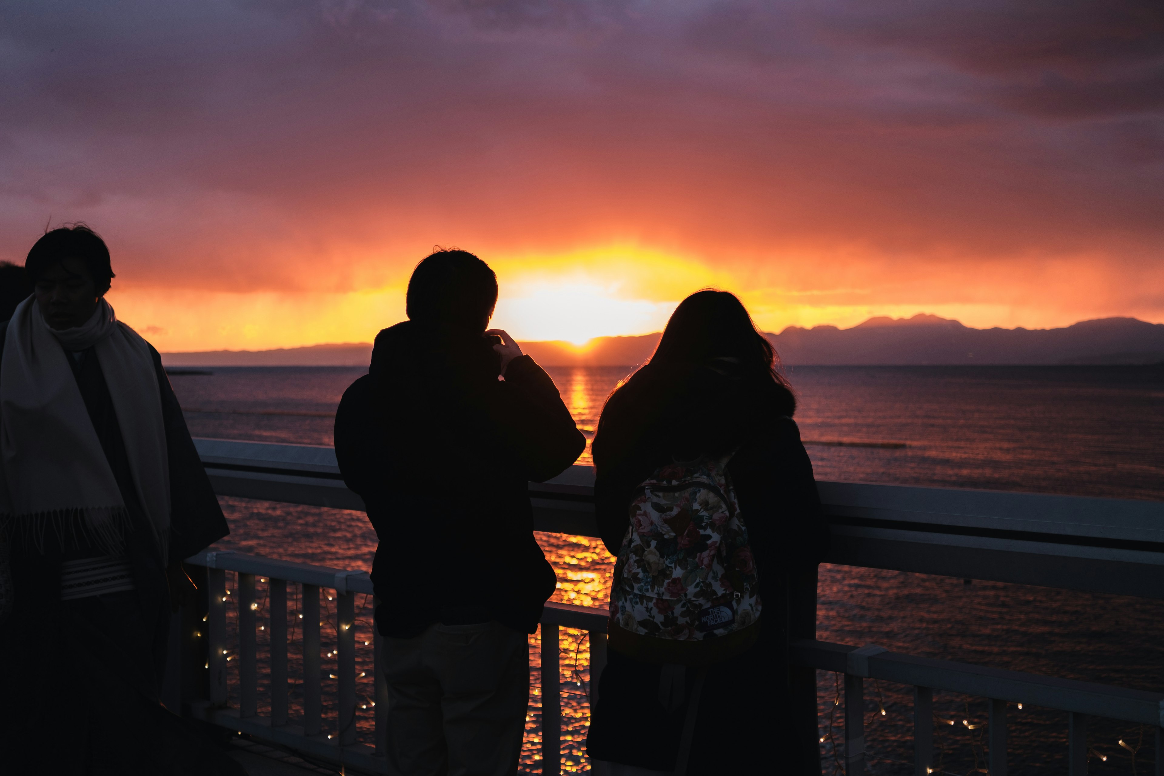 海の景色を背景に夕日を眺める人々