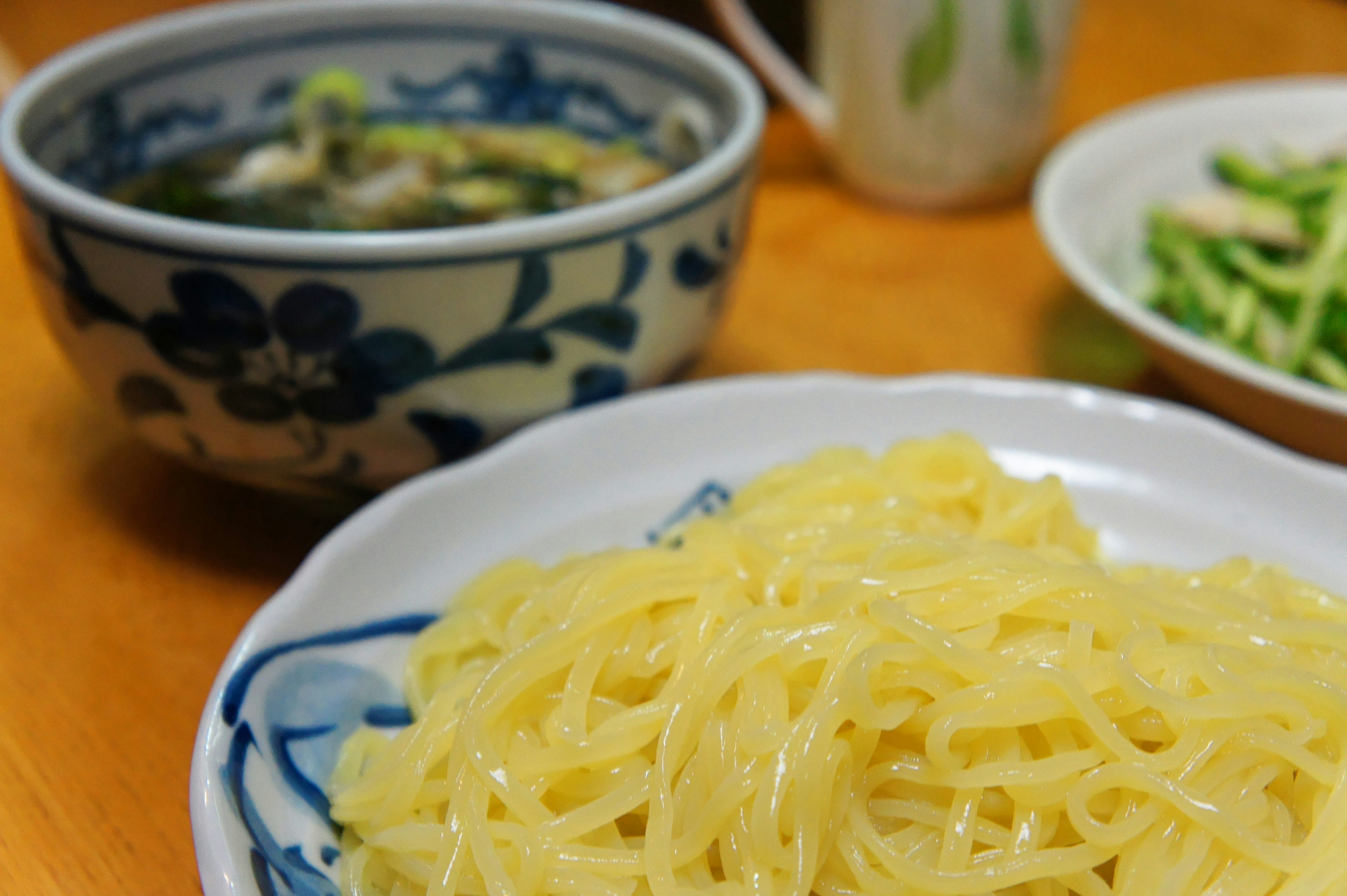 Mie kuning disajikan dalam mangkuk dekoratif di atas meja kayu