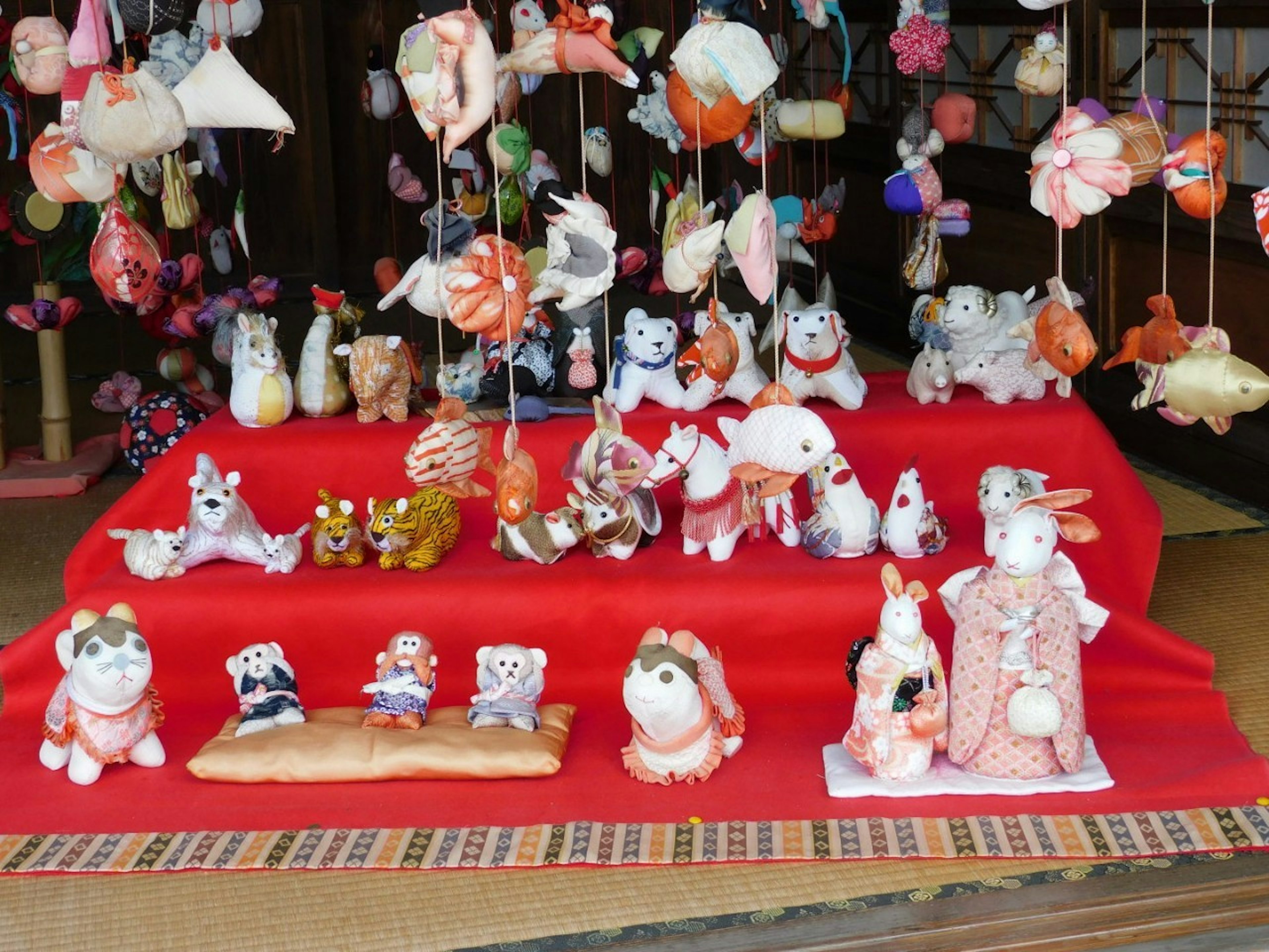 Animales de cerámica adorables exhibidos sobre una tela roja con decoraciones colgantes