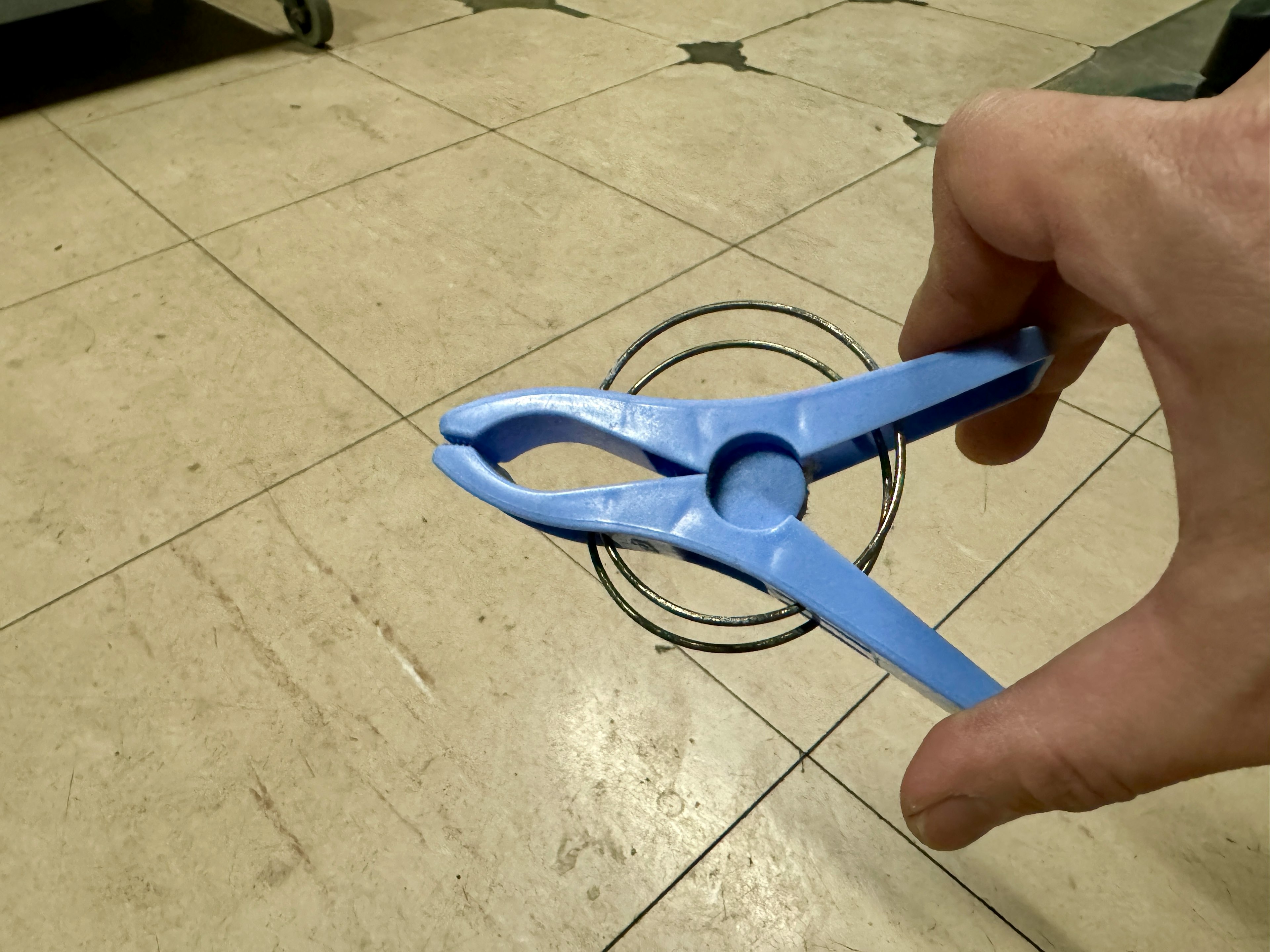 Hand holding a blue compass above a drawn circle on the floor