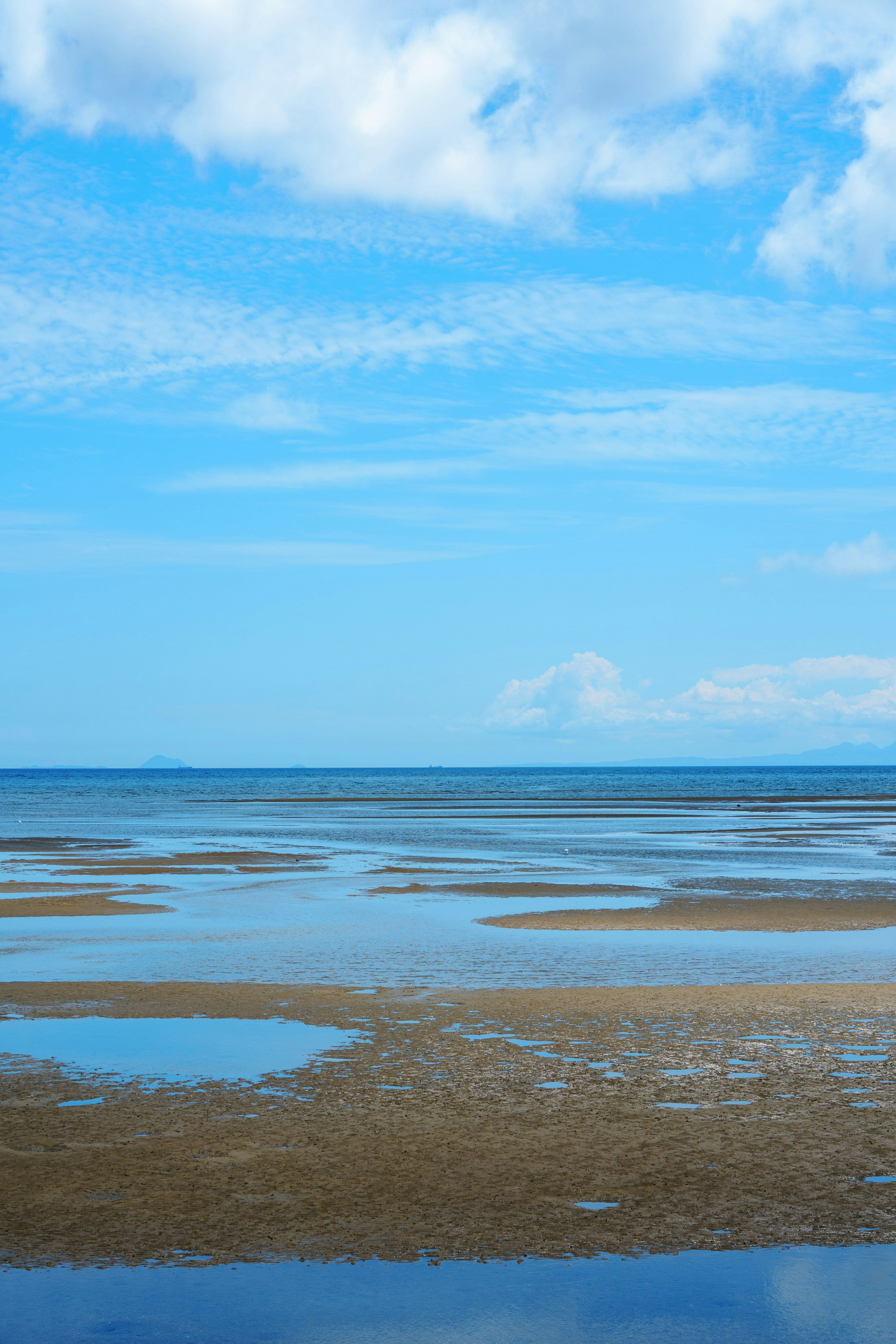 Lahan pasang yang luas dengan langit biru dan laut tenang