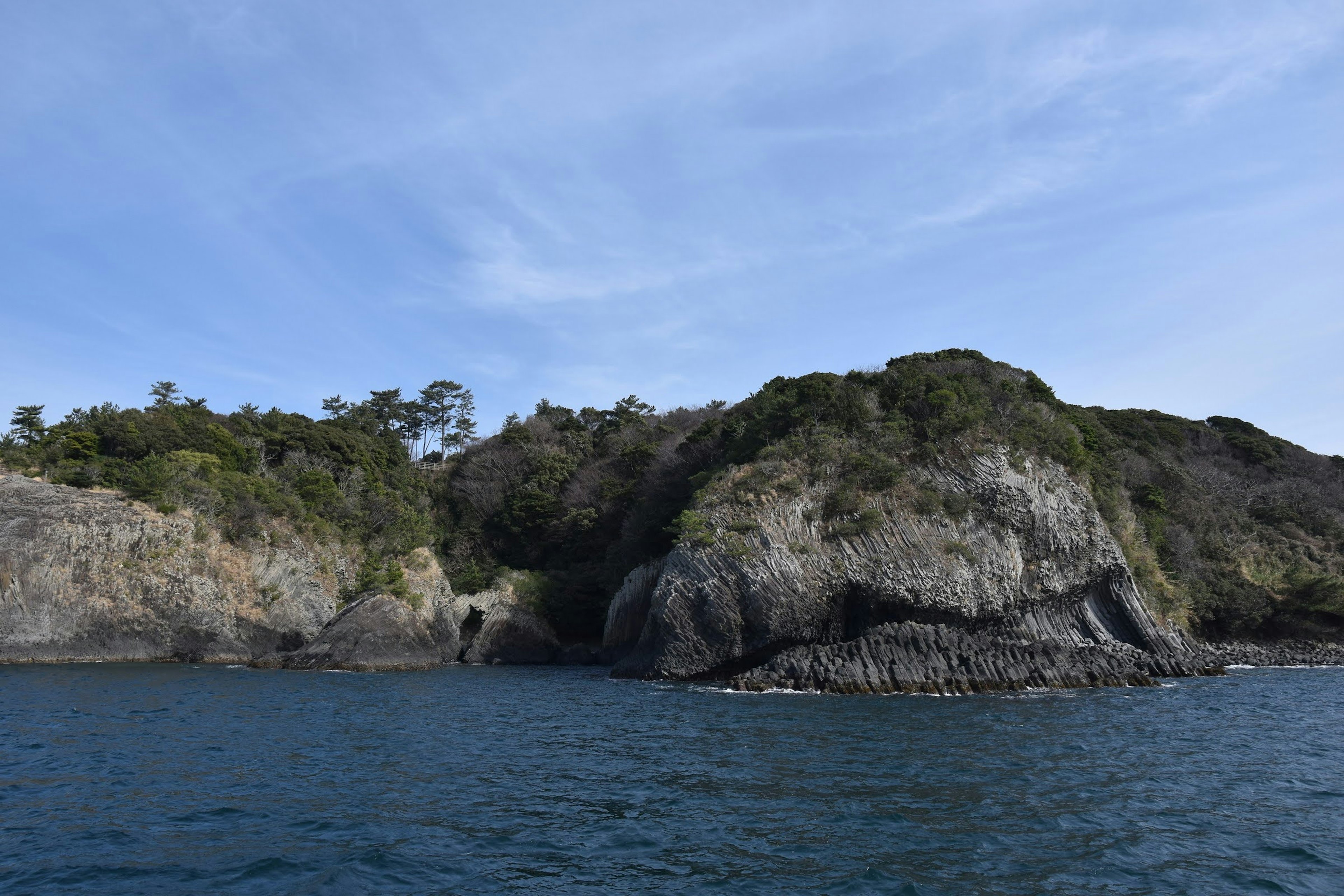 Hermoso paisaje costero con rocas y árboles bajo un cielo azul