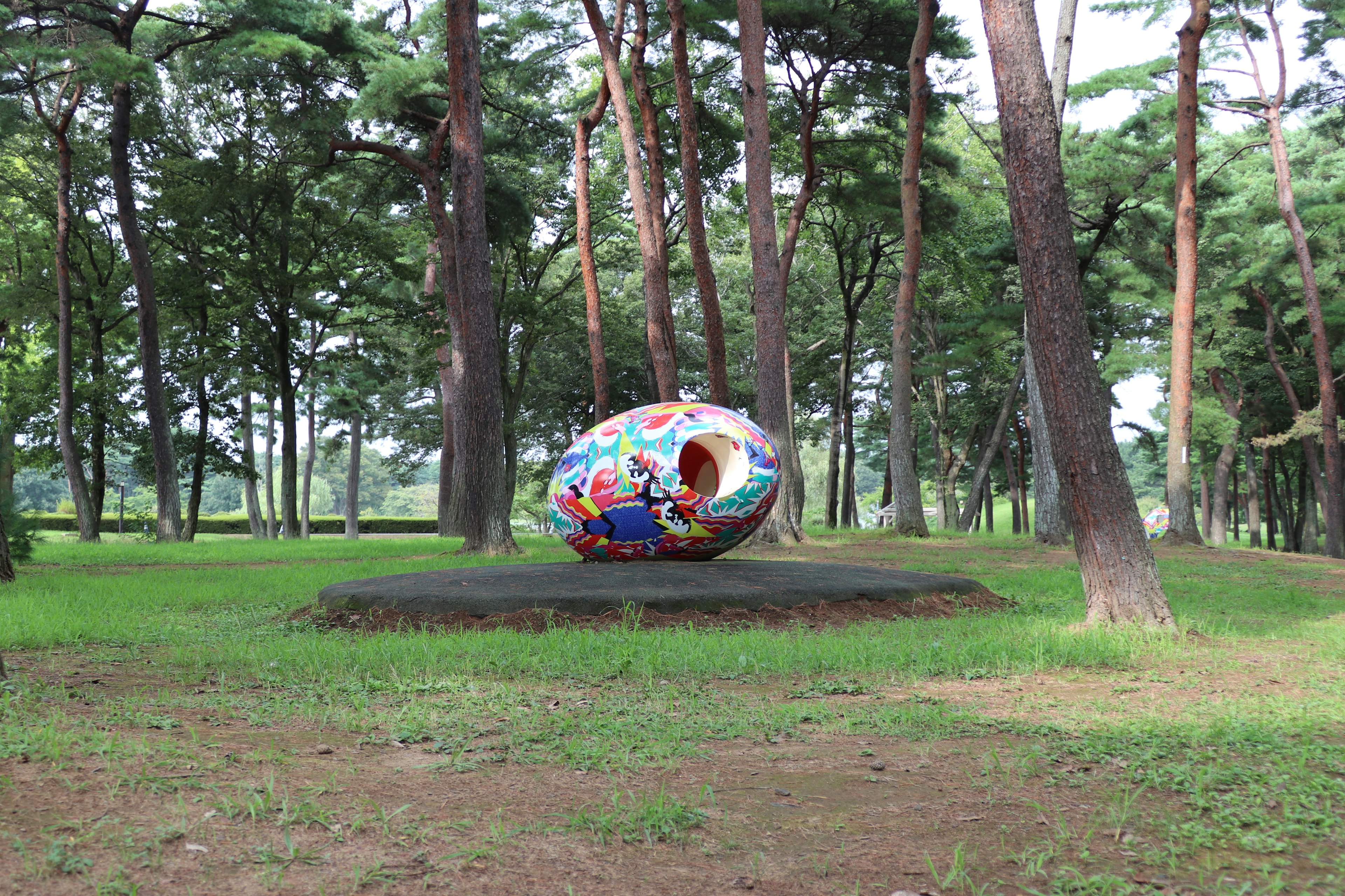 綠色公園中被樹木環繞的多彩裝飾雕塑