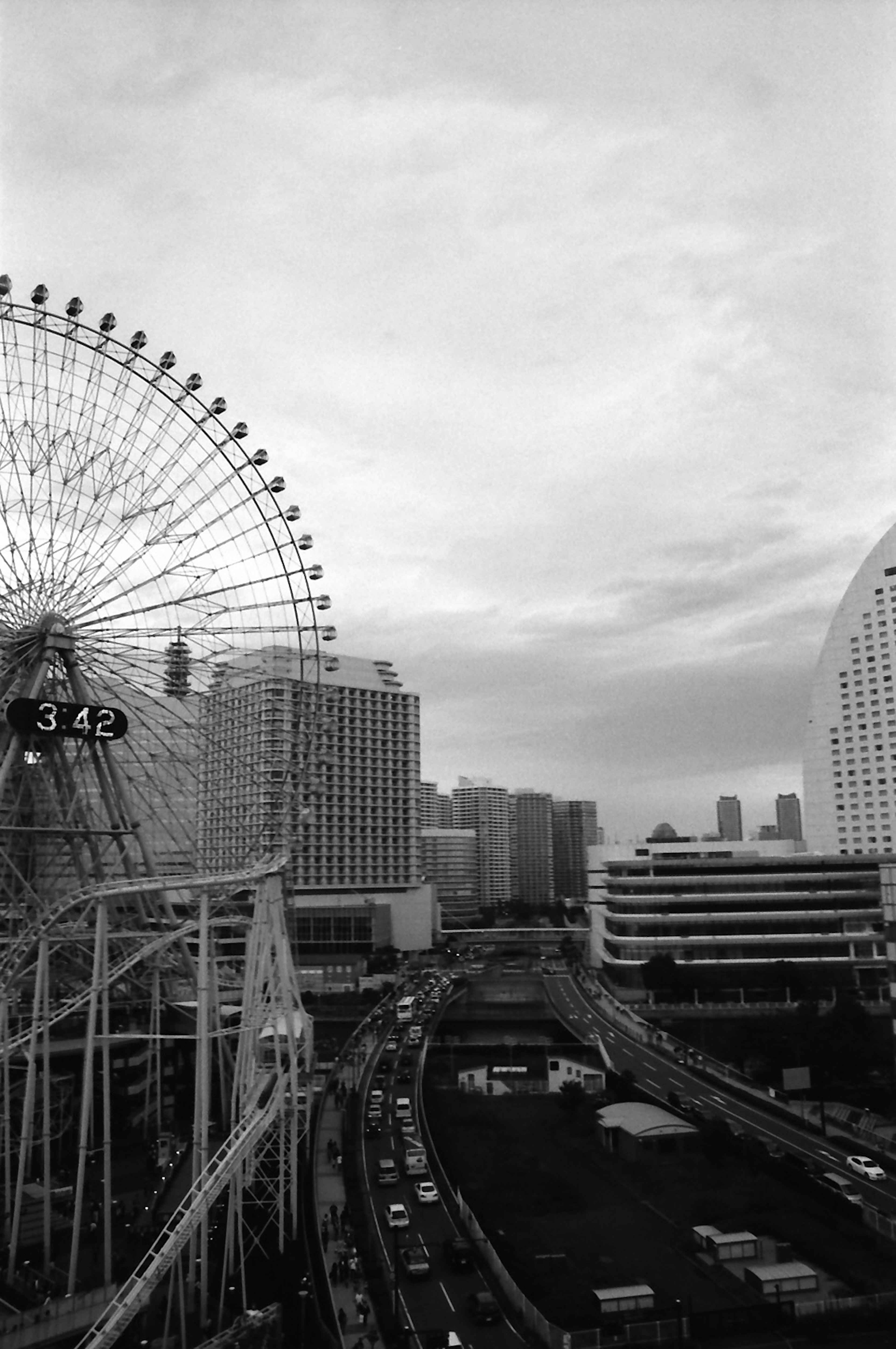 Image en noir et blanc présentant une grande roue et un paysage urbain