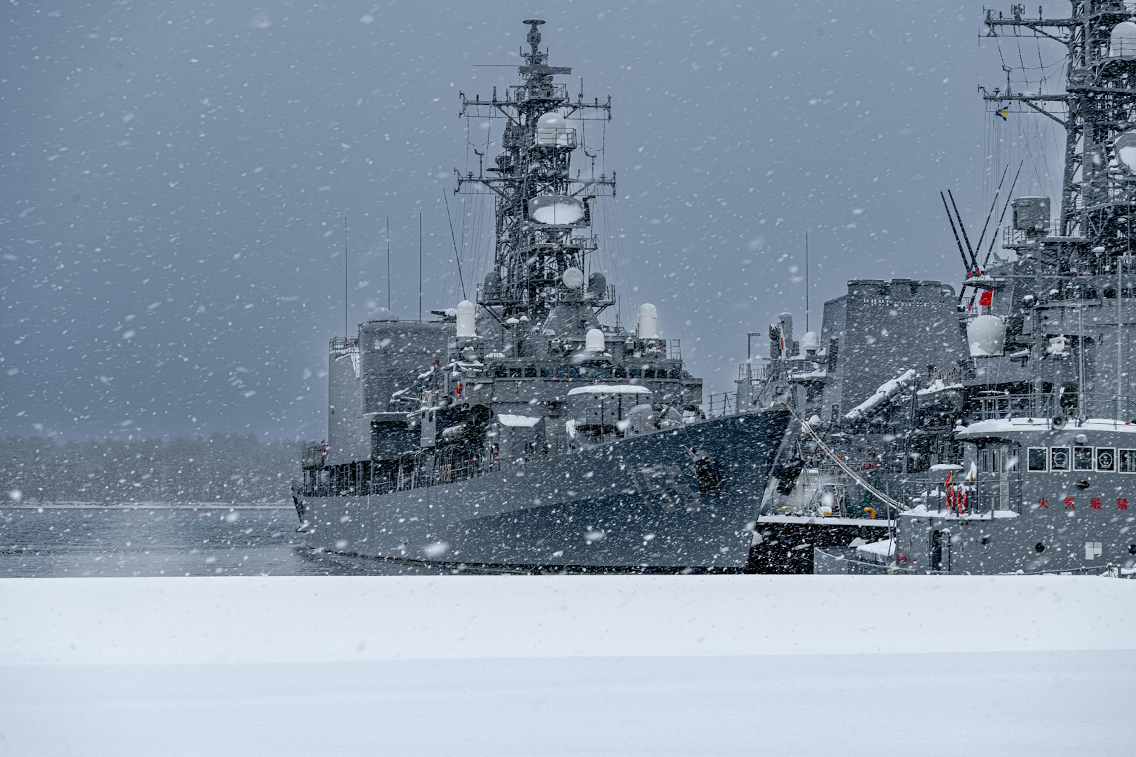 Military ships docked in snow with a gray sky