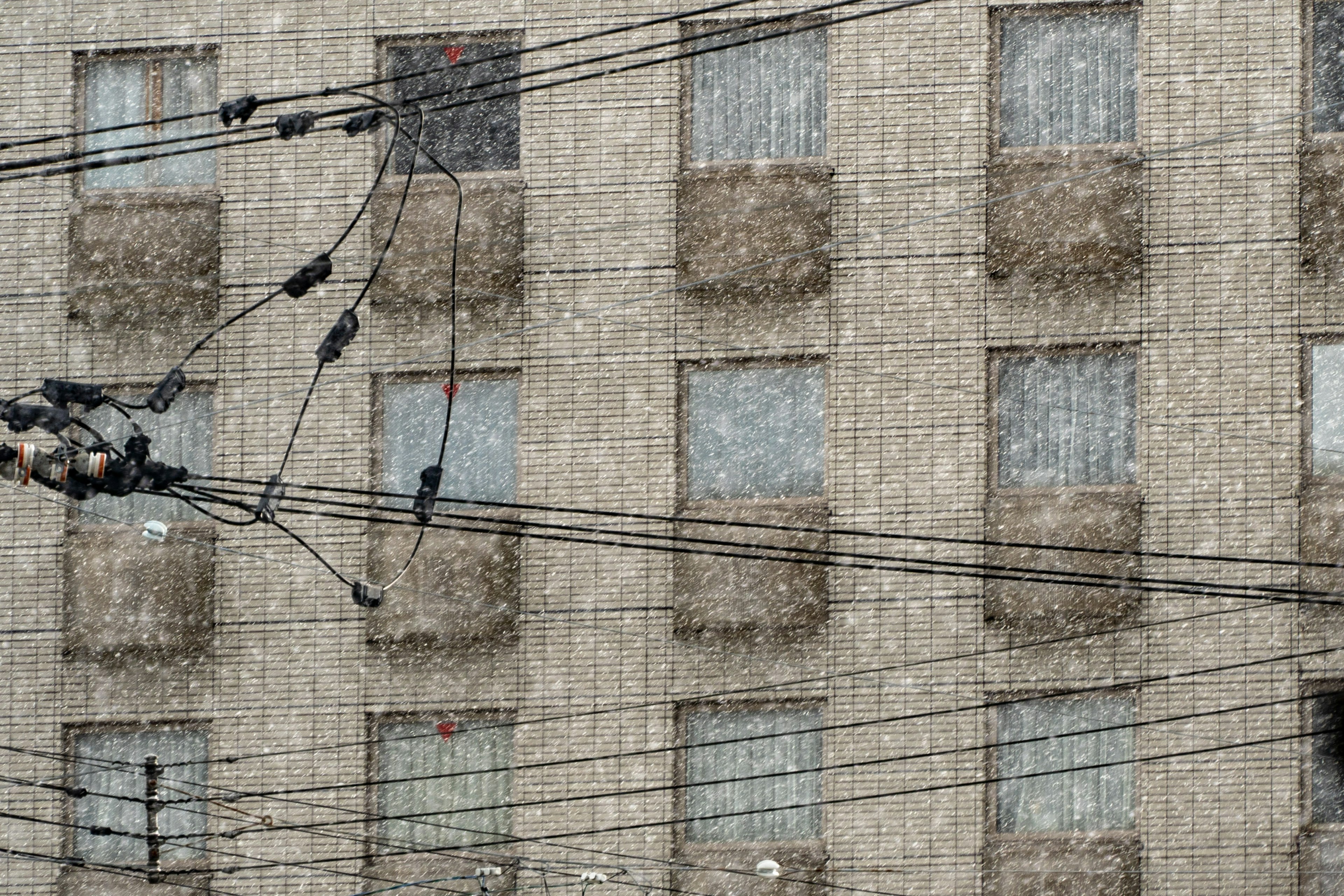 Nieve cayendo sobre la fachada de un edificio con líneas eléctricas visibles