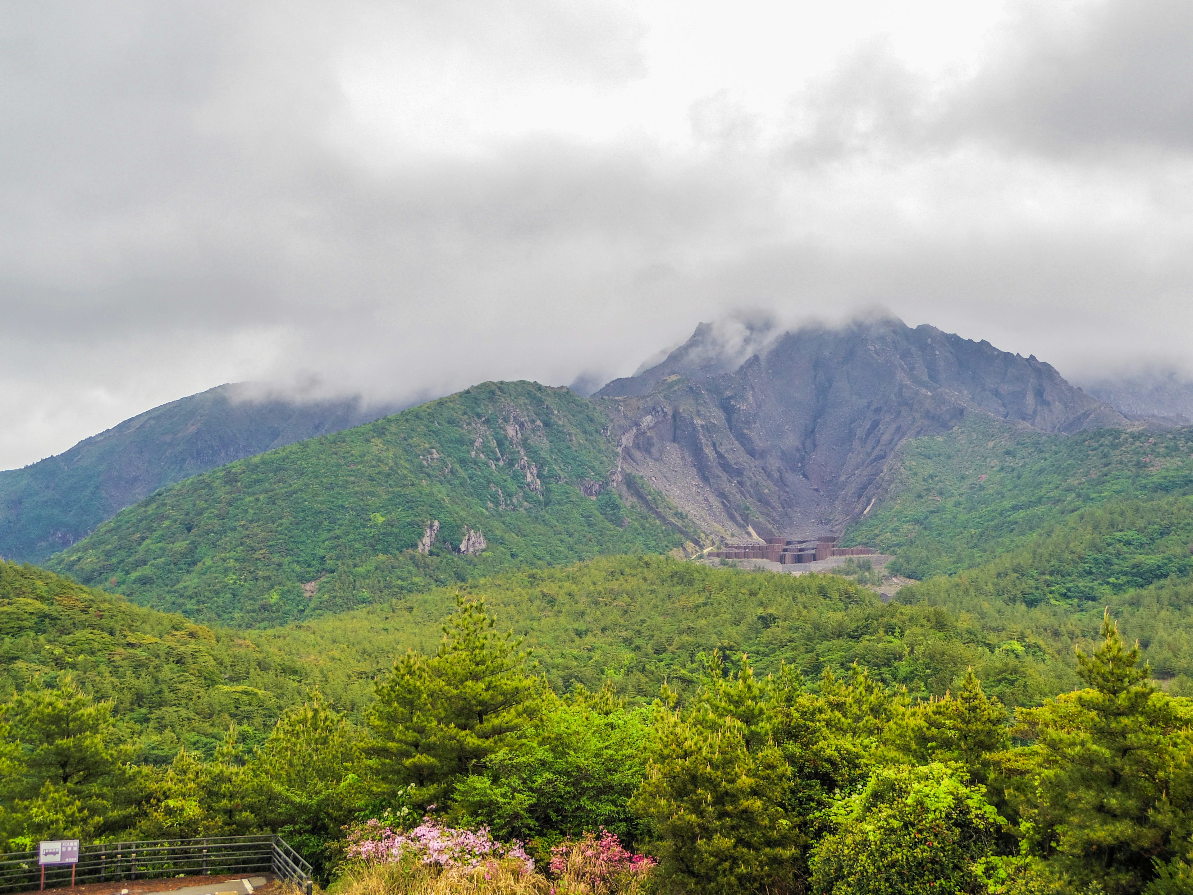 緑豊かな山々と雲に覆われた山頂が特徴の風景