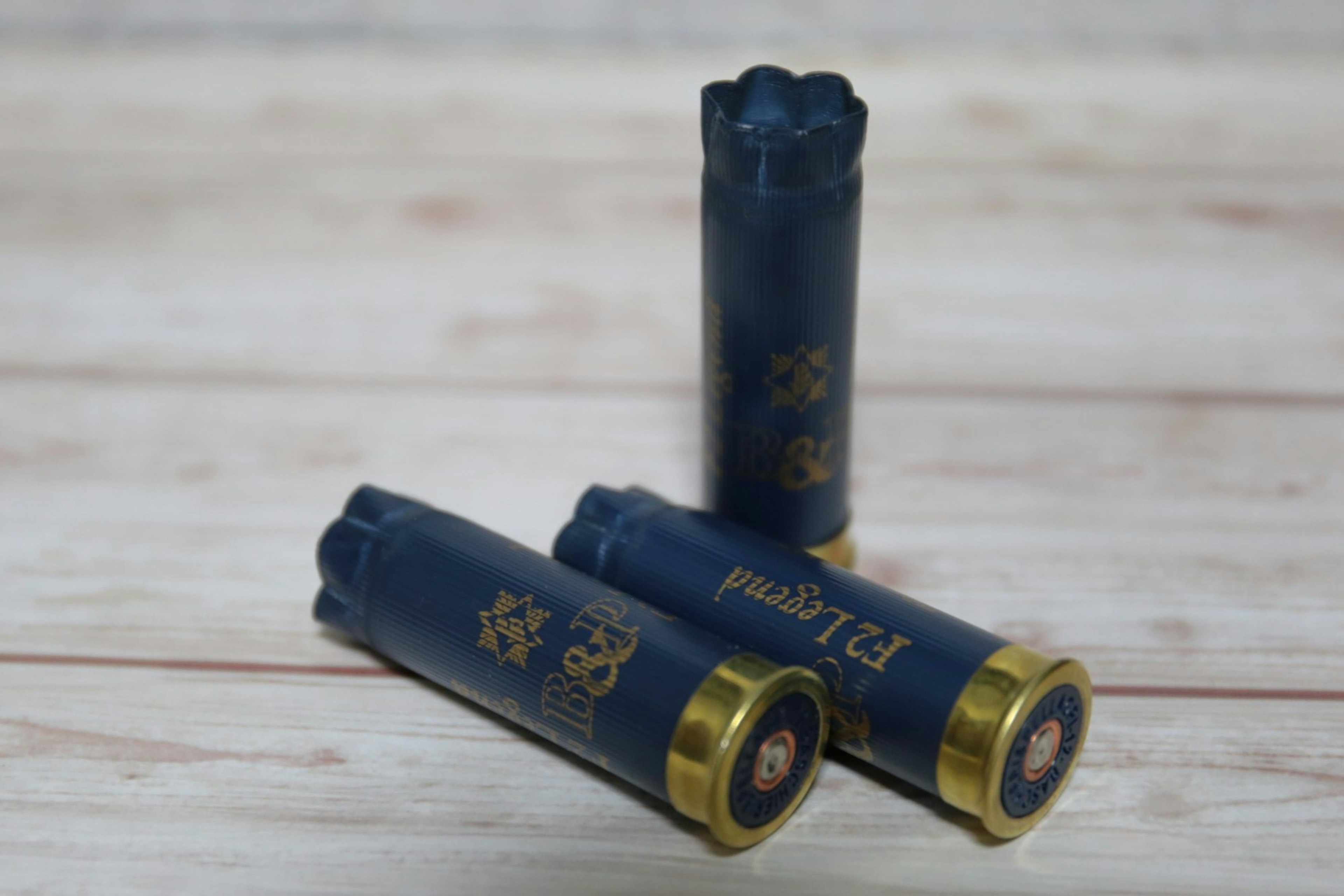 Tiga peluru shotgun biru dengan dasar emas disusun secara artistik