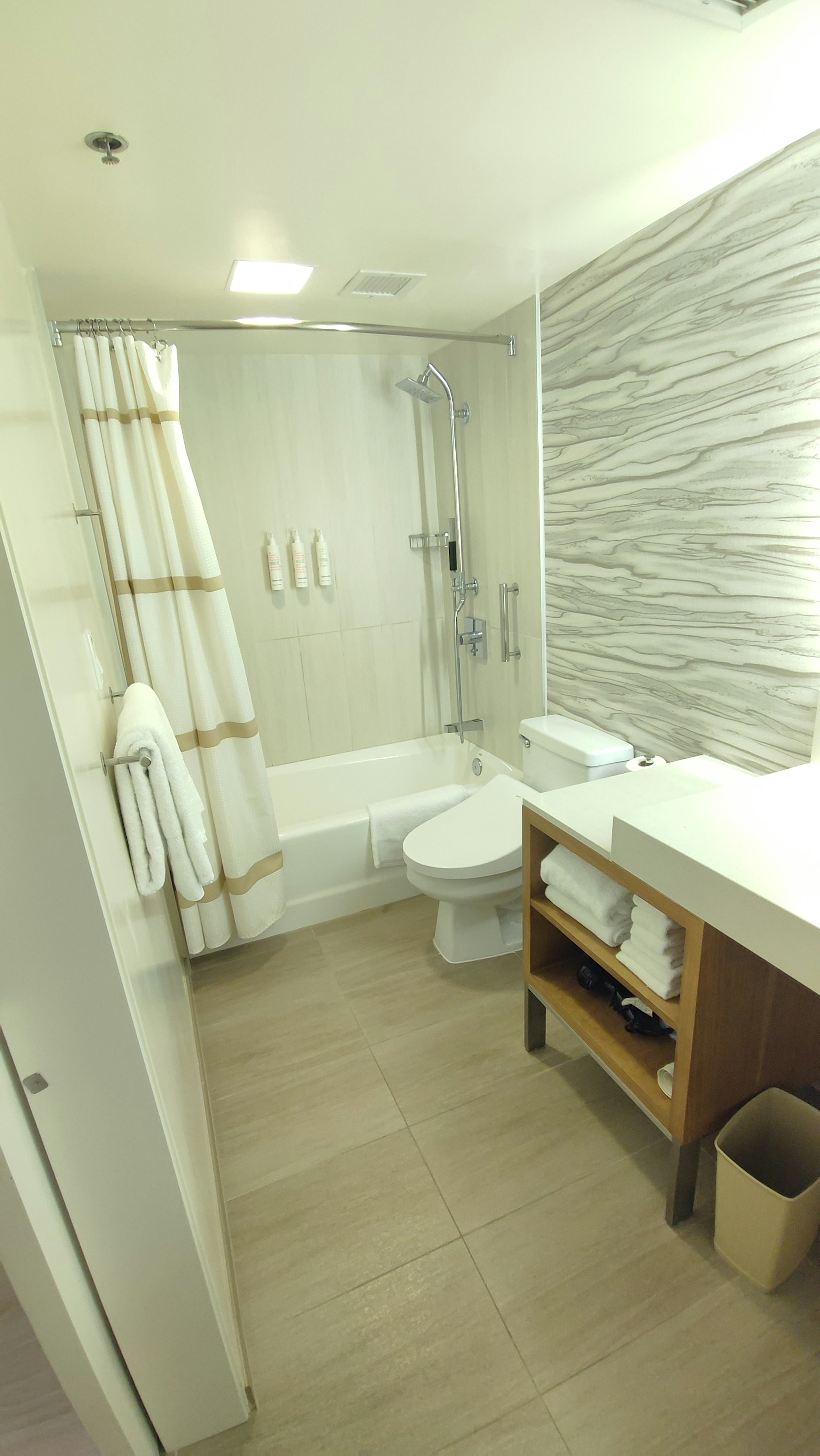 Modern bathroom featuring a bathtub and shower with neatly arranged towels and amenities