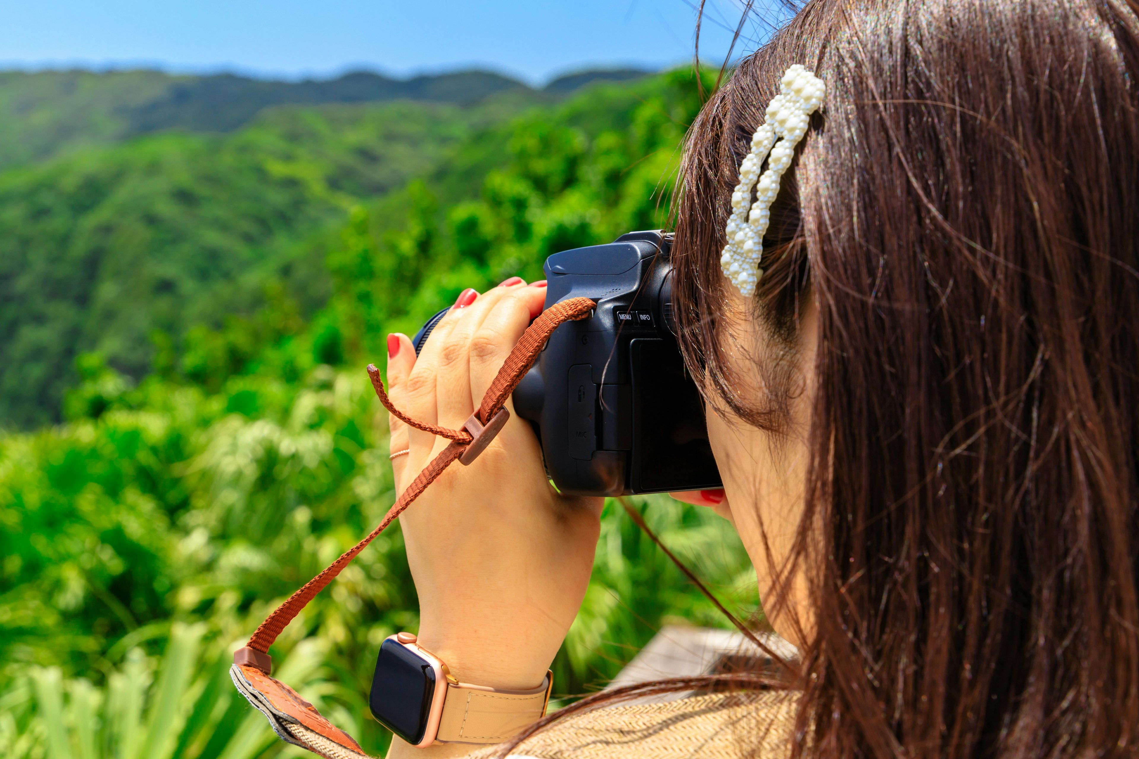 Donna che tiene una macchina fotografica con montagne verdi sullo sfondo