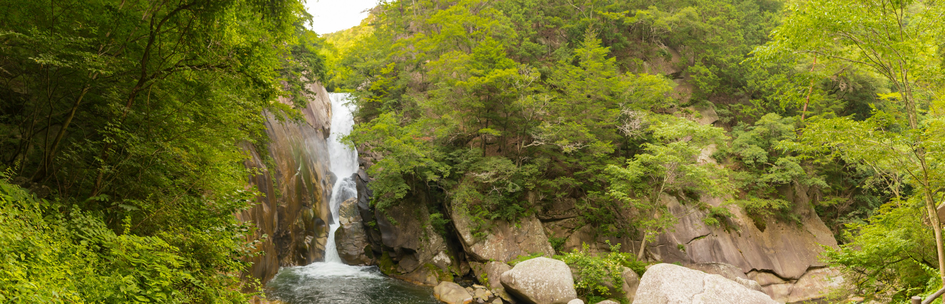 Una cascata che scorre tra montagne verdi circondate da rocce