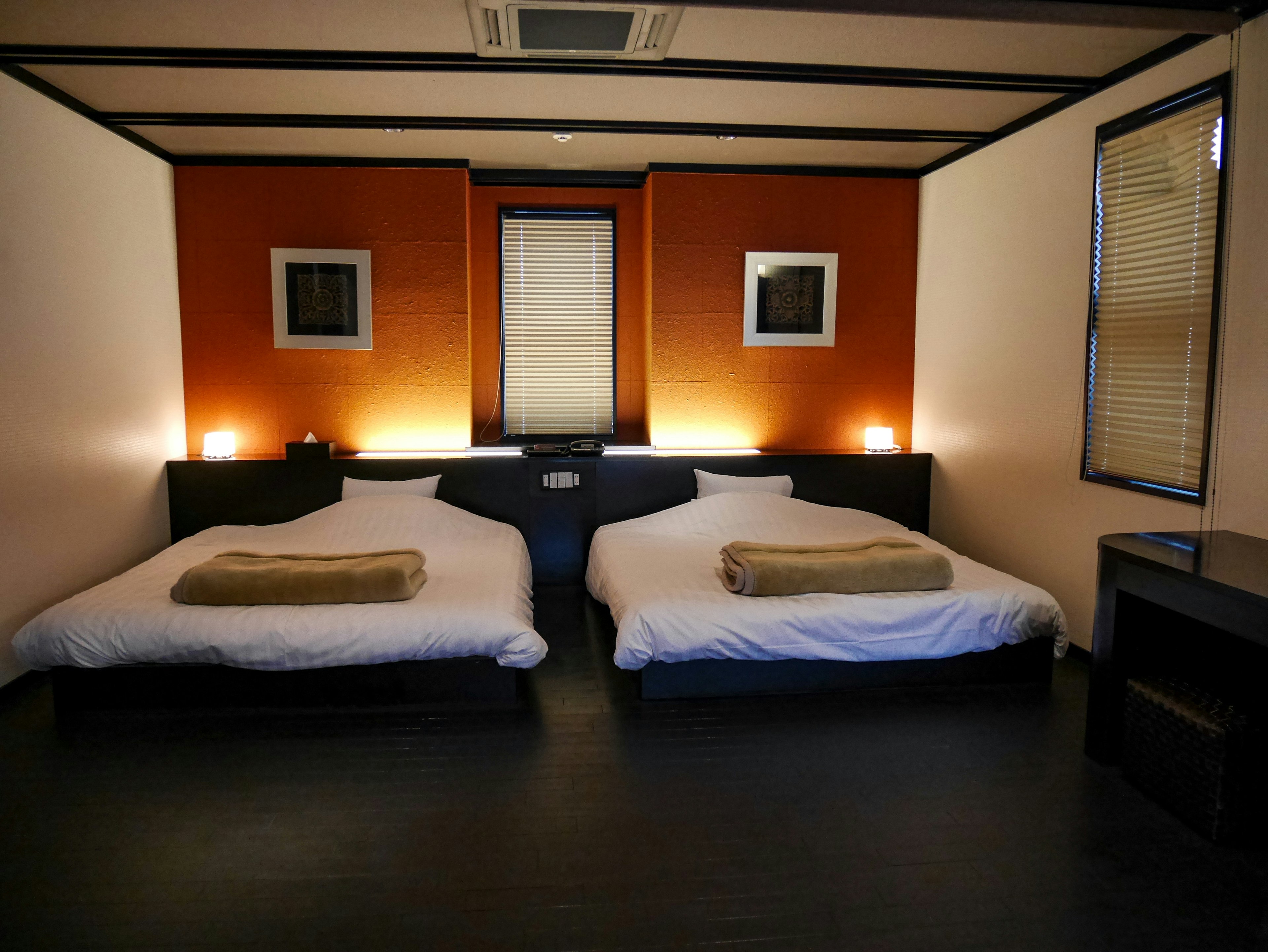 A simple Japanese-style room featuring two beds and warm lighting creating a calming atmosphere