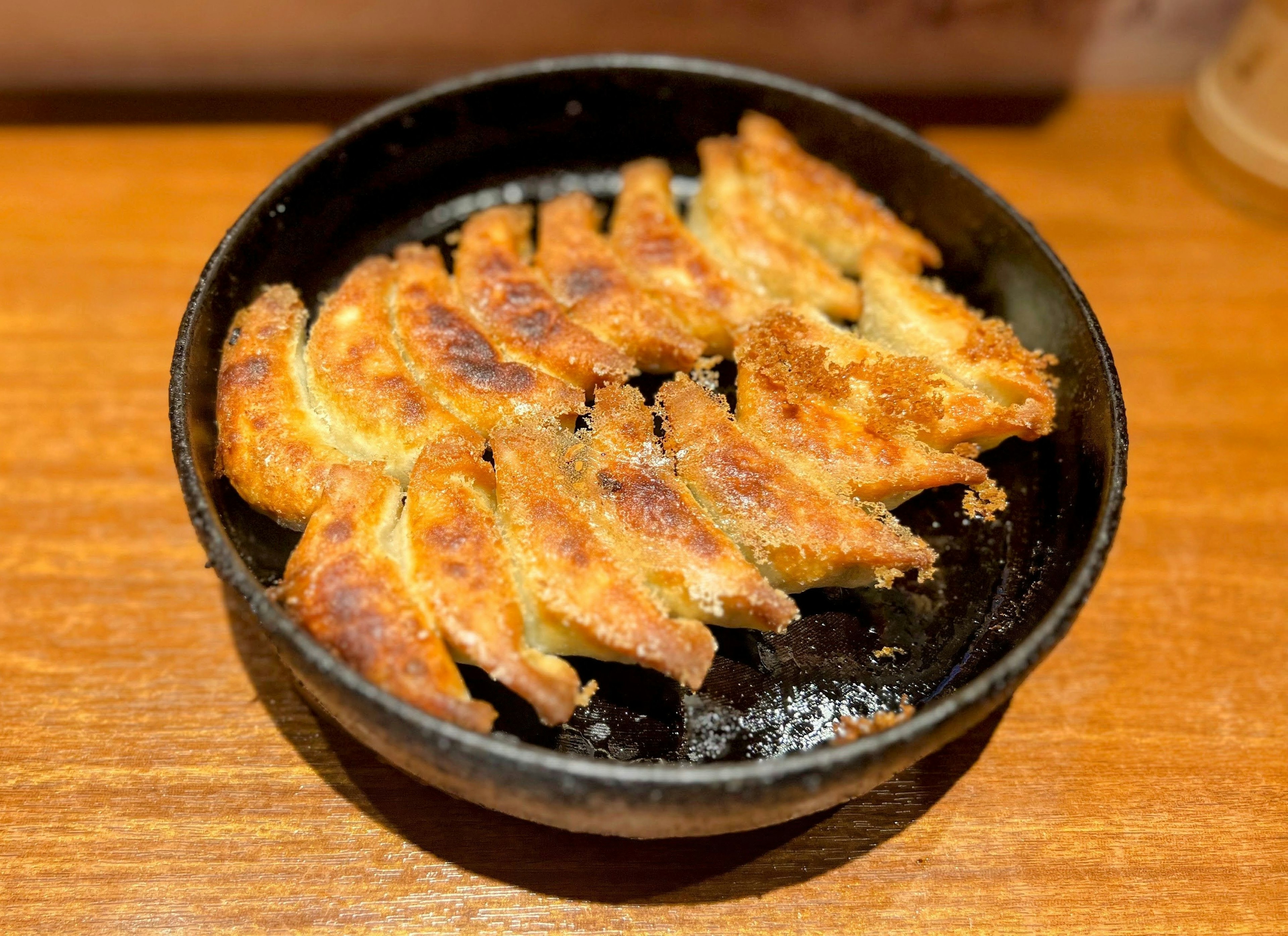 焼き餃子が黒い皿に盛られている