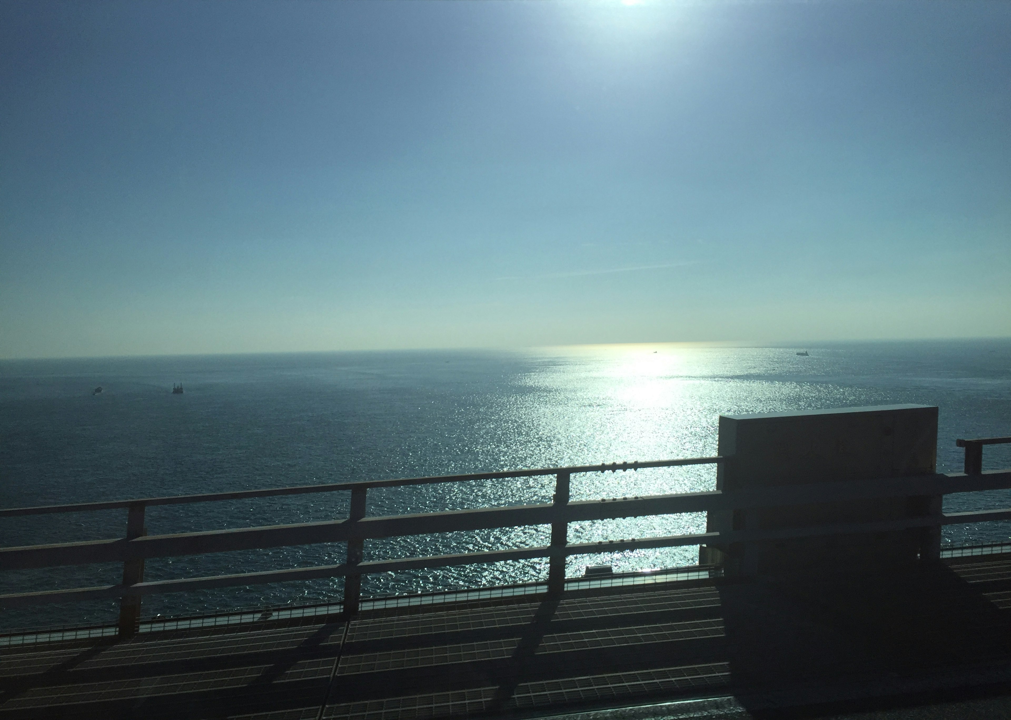 Vista escénica de la luz del sol reflejándose en el océano con un cielo azul claro