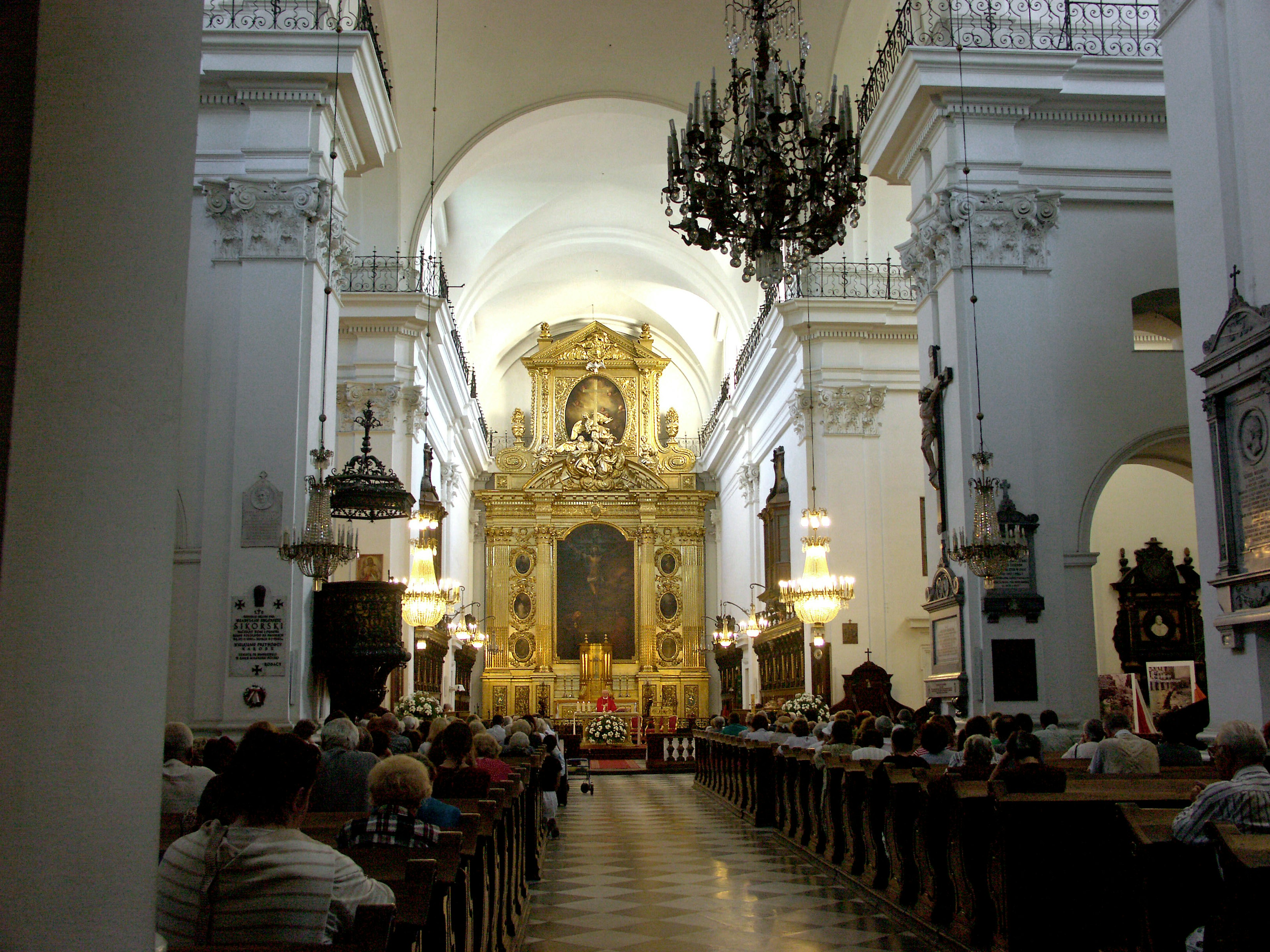 Innere einer Kirche mit aufwendigen Verzierungen farbenfroher Beleuchtung und sitzenden Gläubigen