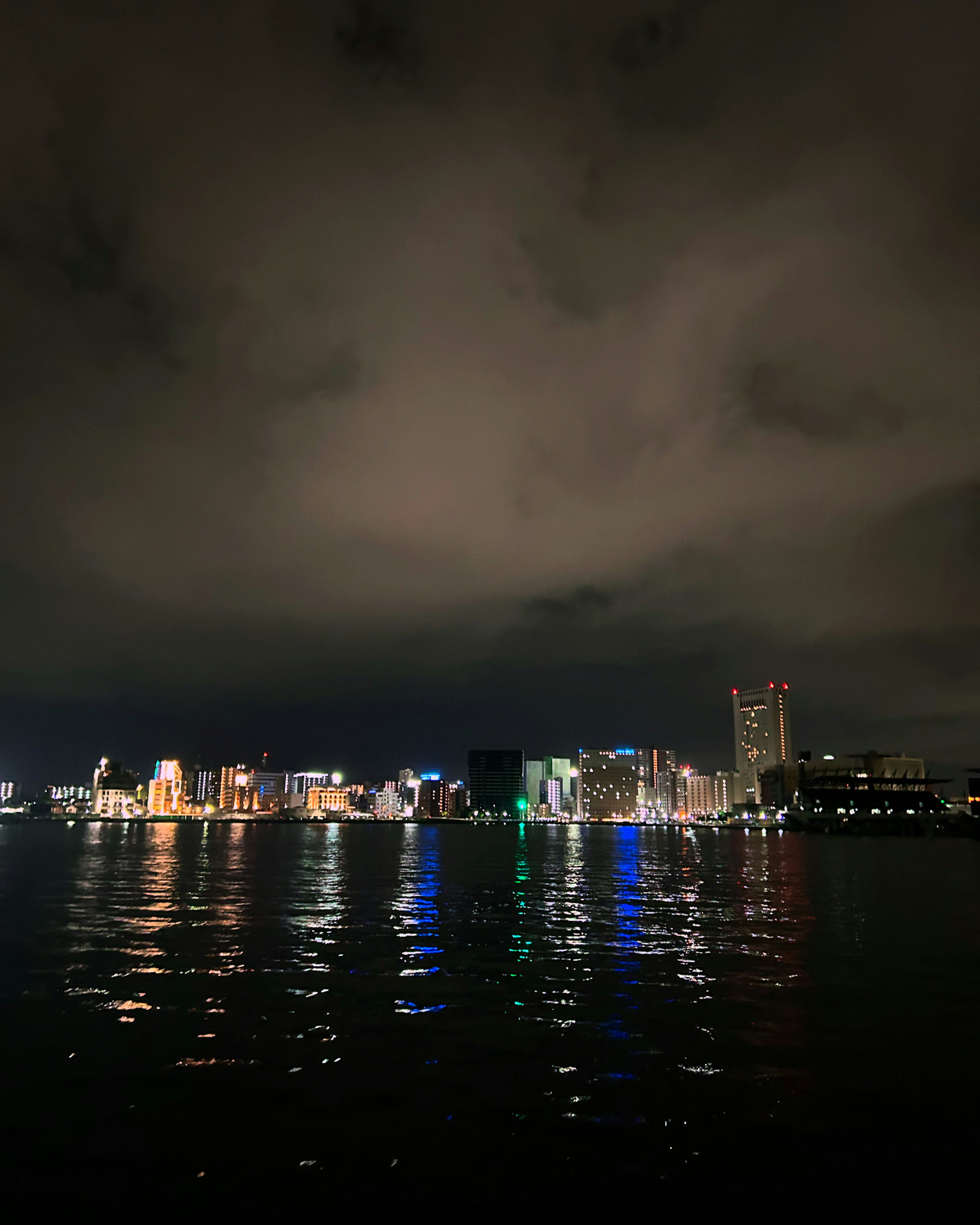 Paesaggio urbano notturno con riflessi sull'acqua e nuvole