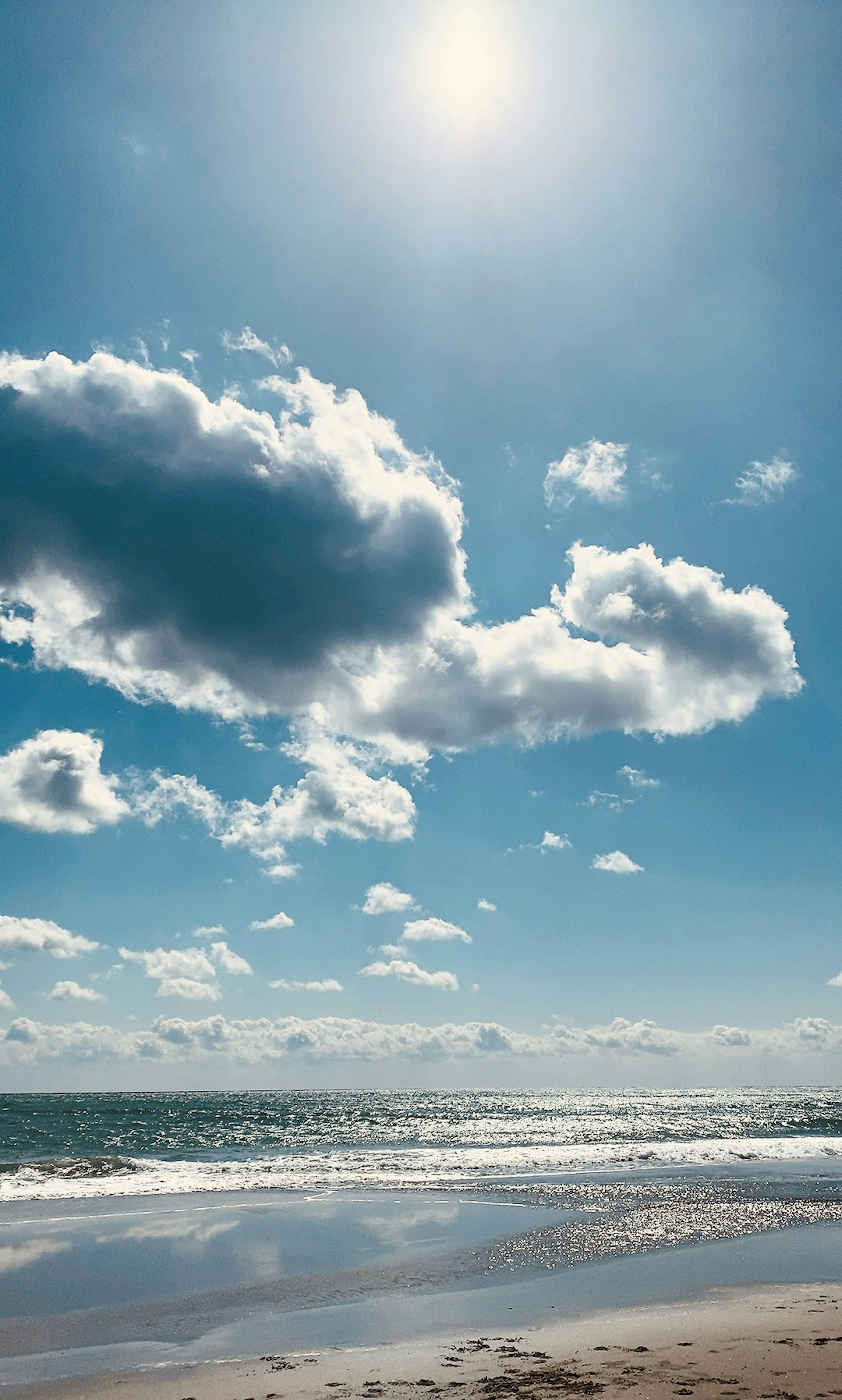 A scenic view of the ocean with blue sky and fluffy white clouds