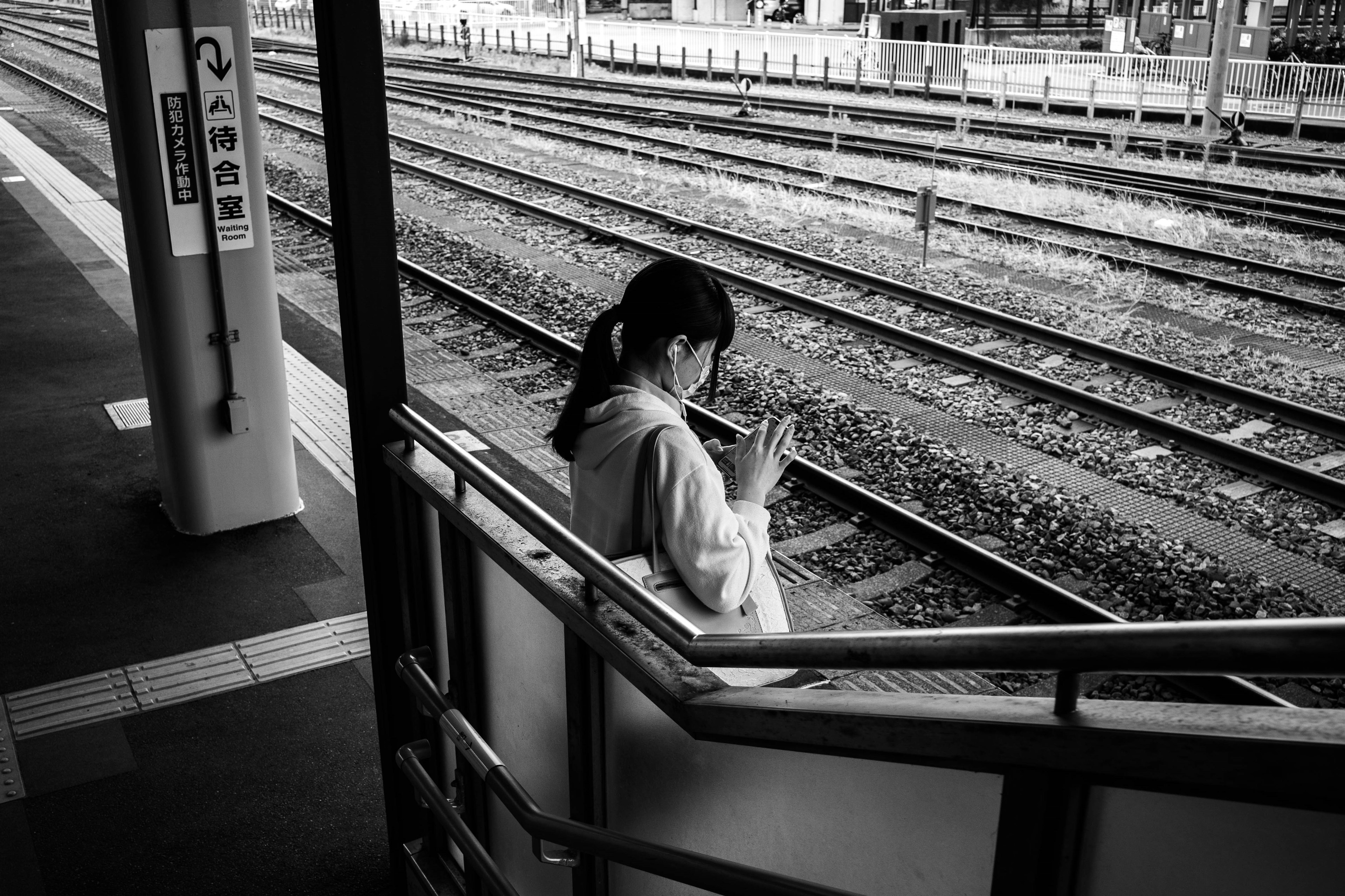 駅のホームで手を合わせている女性のモノクロ写真